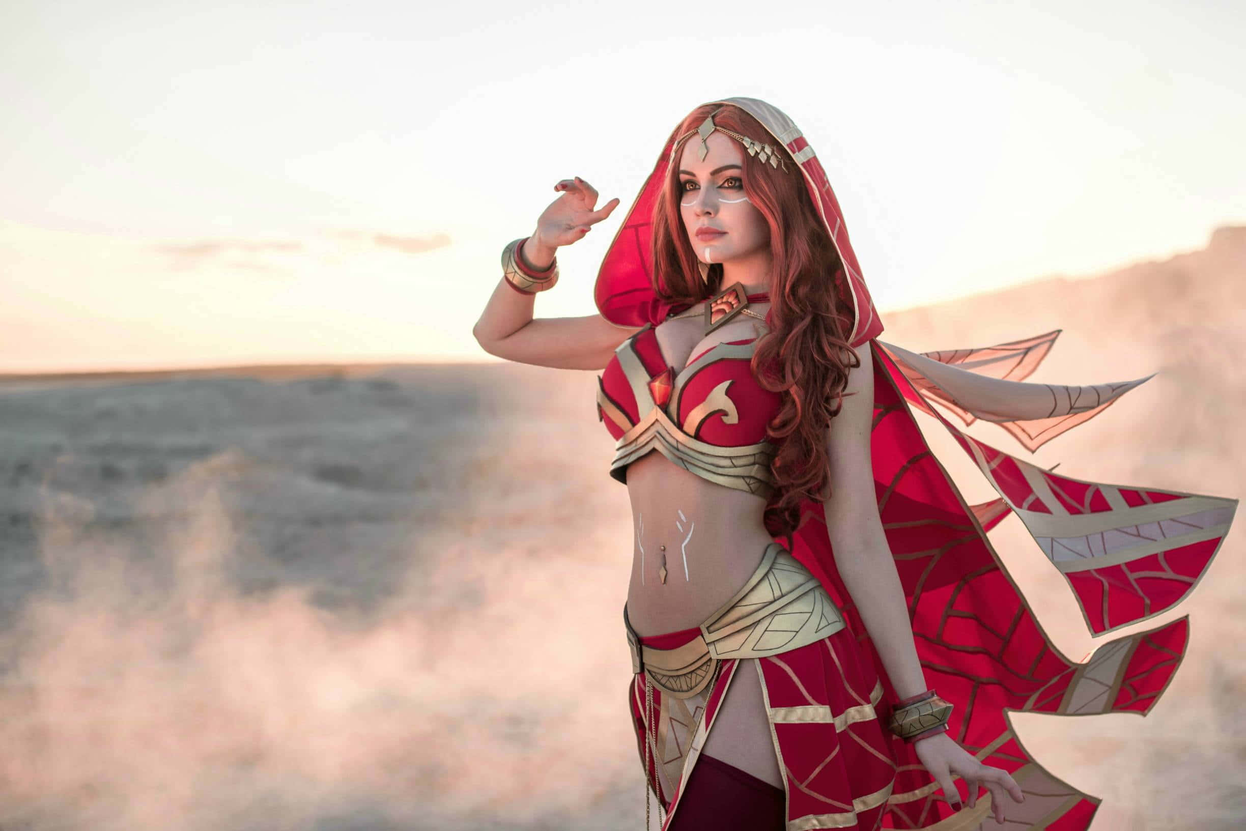 Gaming Cosplay 桌布 壁紙 — 一位角色扮演者身穿紅金奇幻戰士服裝，在日落時分以霧氣瀰漫的沙漠為背景，擺出姿勢。