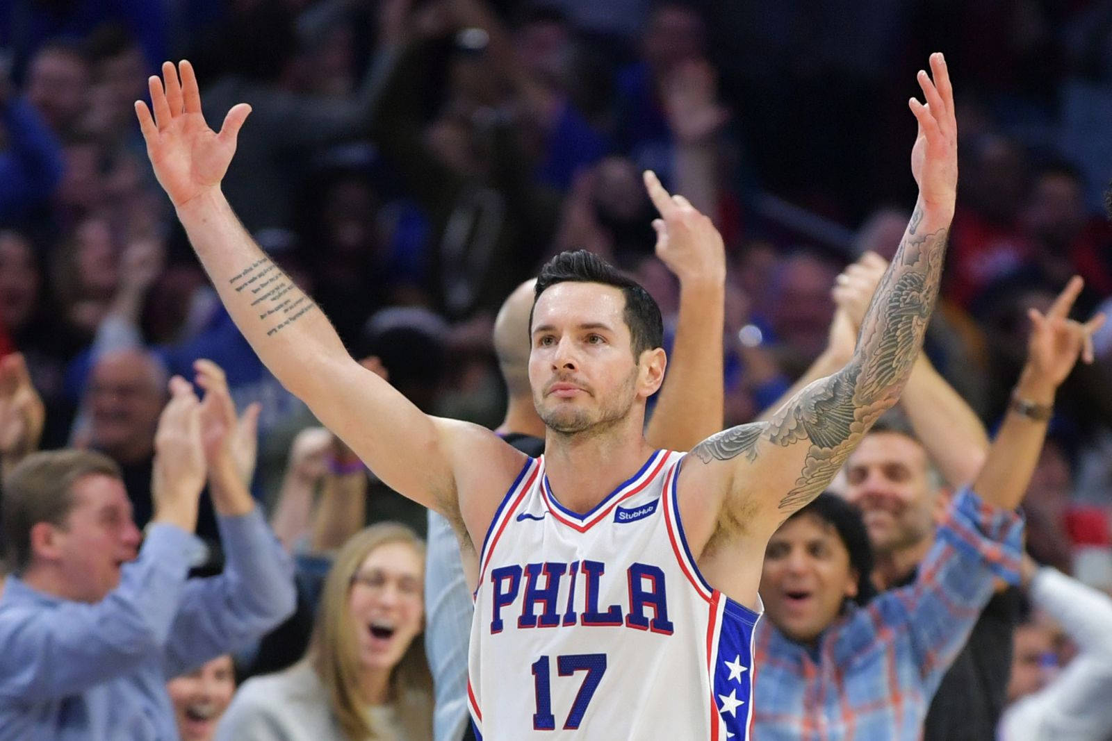 Jj Redick 桌布 壁紙 — 一位費城76人隊的籃球運動員，手臂上有刺青，高舉雙手慶祝勝利，背景是球迷在歡呼。