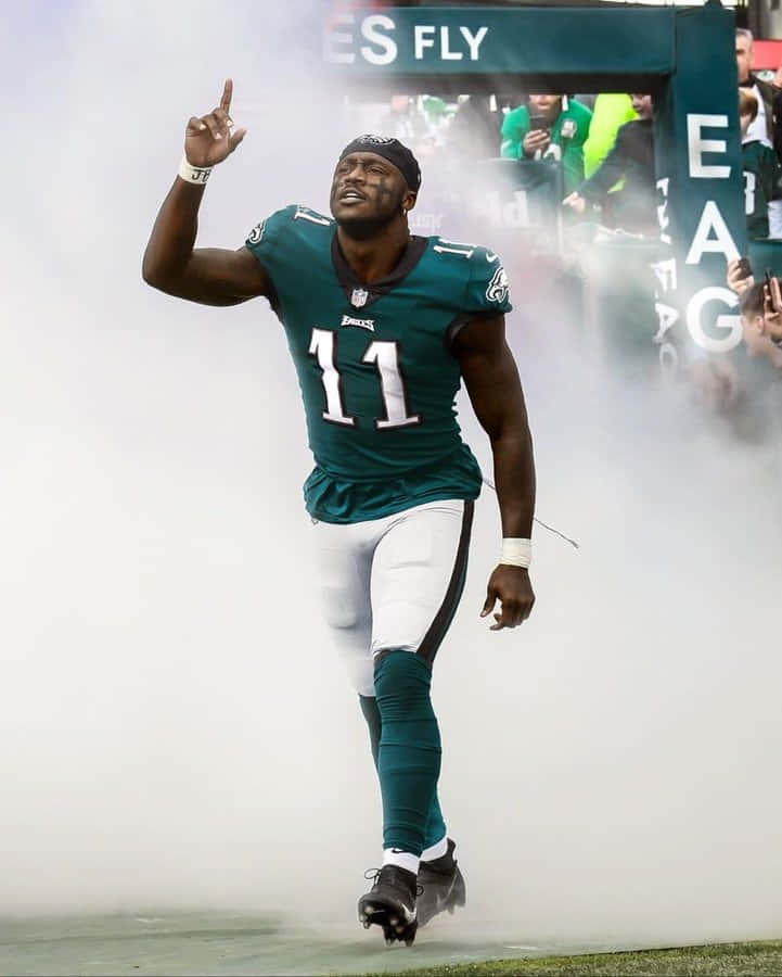 Eagles Football 桌布 壁紙 — 一位費城老鷹隊身穿青綠色11號球衣的足球員，在體育館的煙霧隧道中勝利地出現。