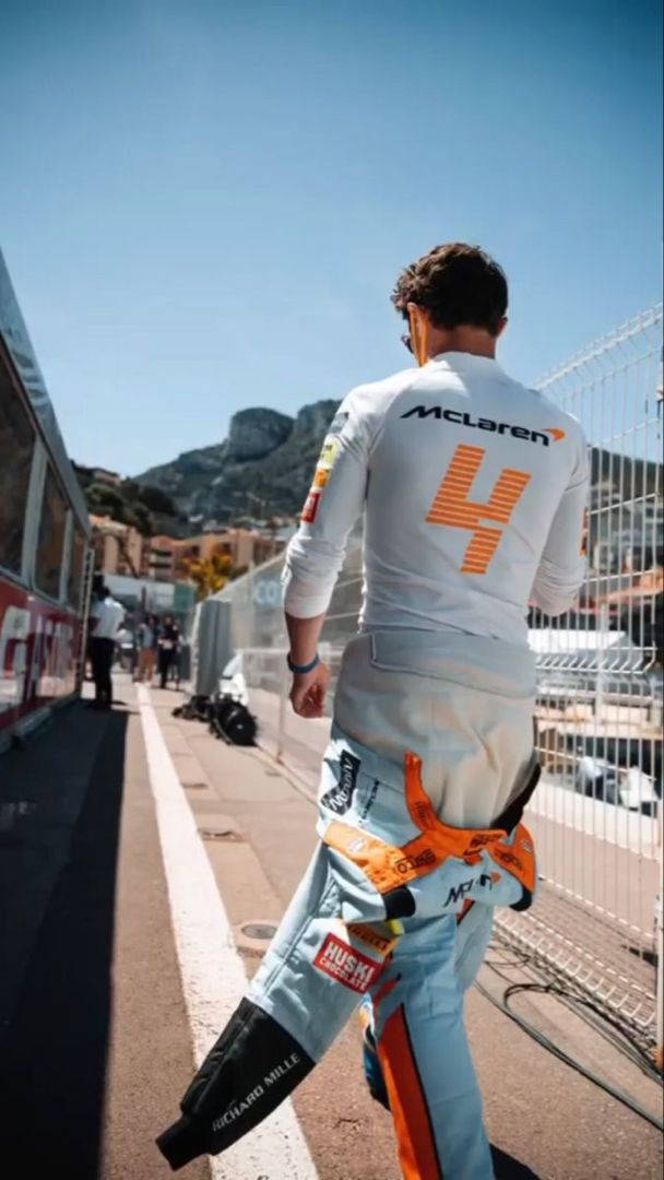 Racing 桌布 壁紙 — 一位賽車手穿著白色McLaren賽車服，號碼4，在陽光明媚的賽道旁小路上遠離鏡頭走去。