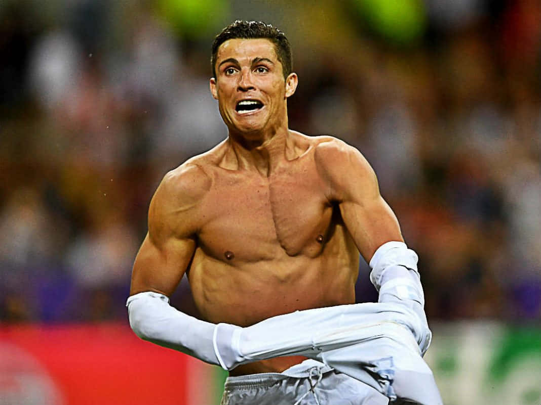 Ronaldo 桌布 壁紙 — 一位赤膊、肌肉發達的足球員在燈火通明的球場上熱情慶祝，背景是模糊的球迷。
