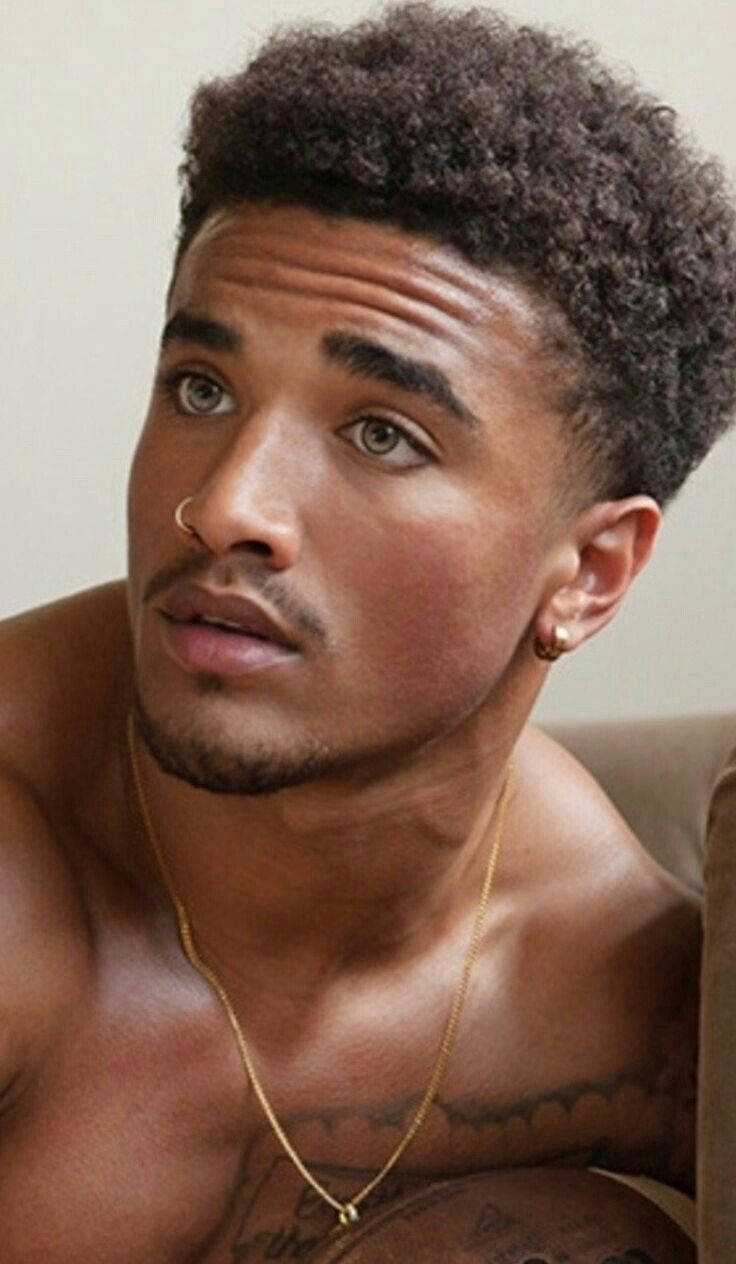 手機 桌布 壁紙 — 一位赤膊的年輕男子，留著捲髮，佩戴金飾，若有所思地凝視著相機。