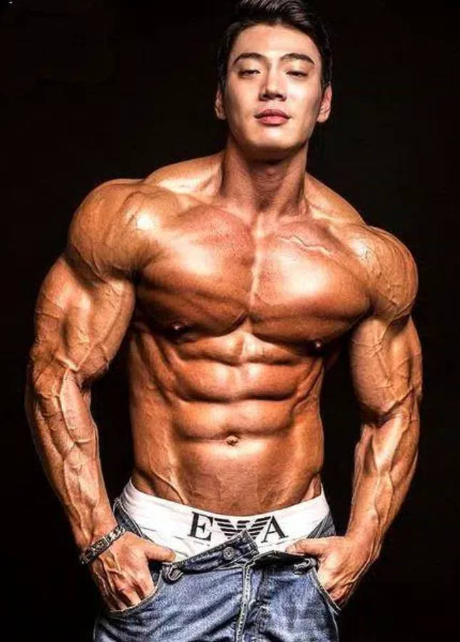 Exercise 桌布 壁紙 — 一位赤膊的肌肉男，擁有清晰的腹肌和手臂線條，在黑色背景前自信地擺姿勢，穿著牛仔褲和品牌內褲。