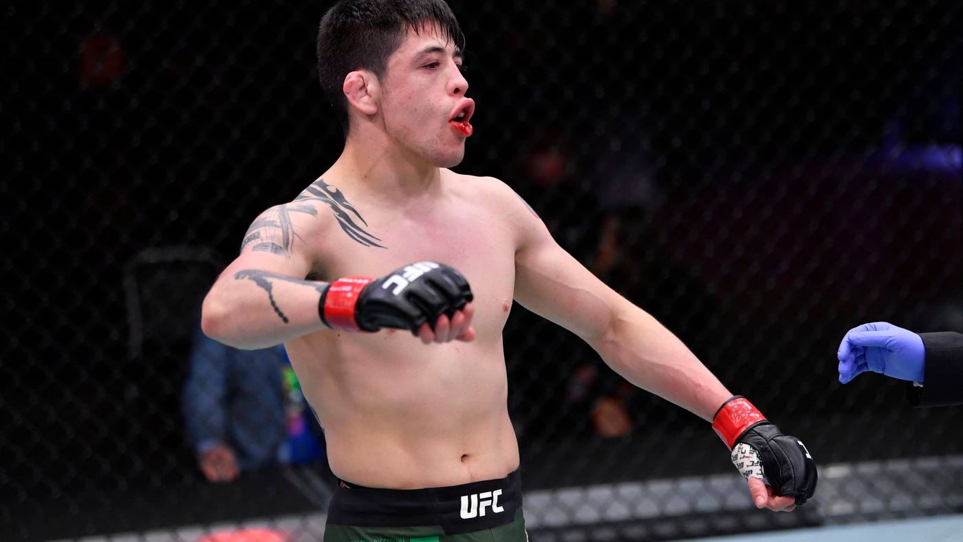 Brandon Moreno 桌布 壁紙 — 一位赤裸上身、有刺青的混合武術家在UFC八角籠內慶祝，嘴唇上有血。