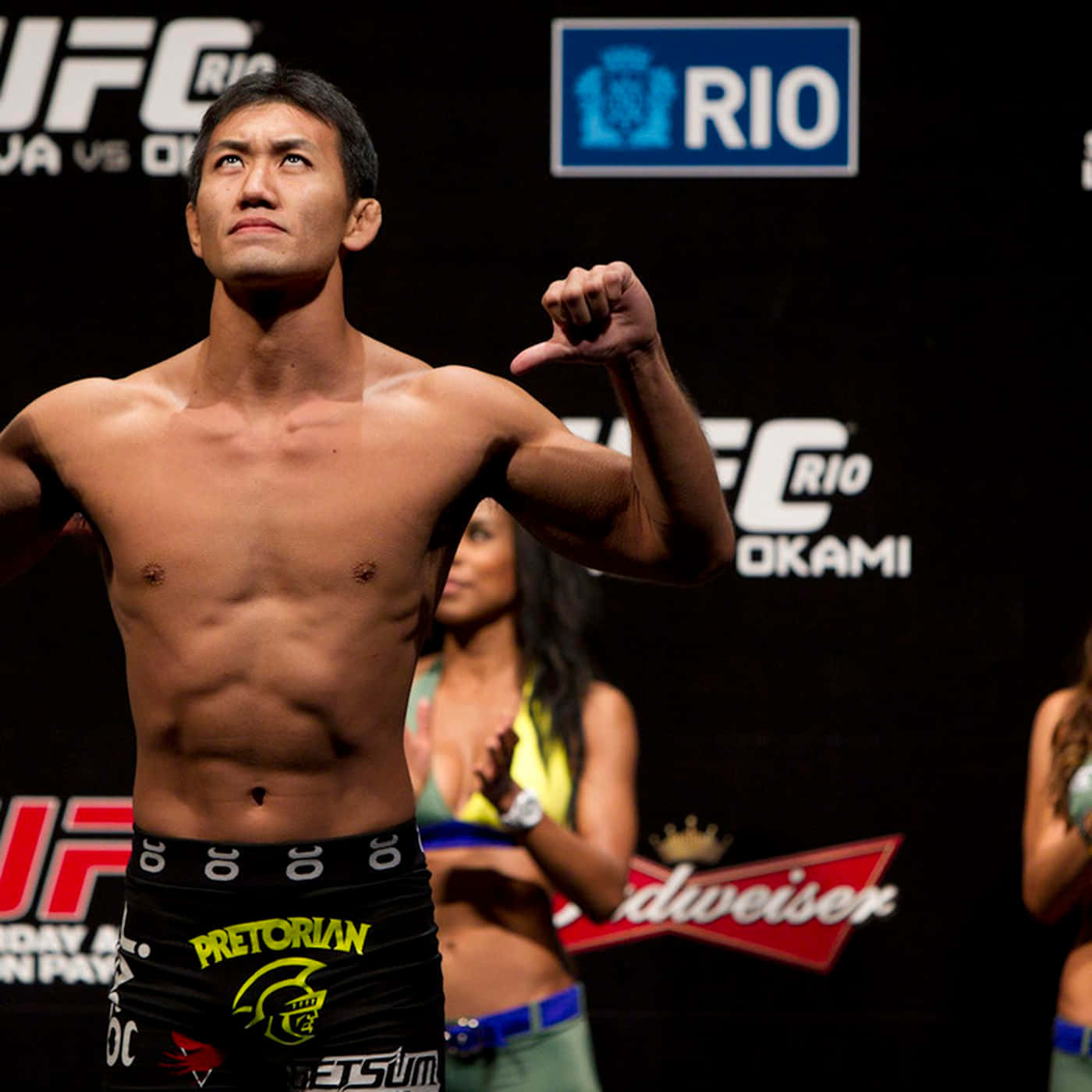 UFC 桌布 壁紙 — 一位赤裸上身的UFC拳手在里約的稱重活動中自信地微笑並展示肌肉。