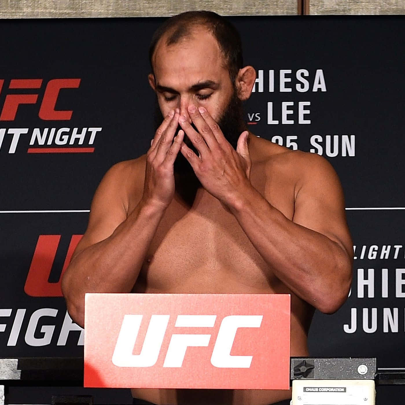 MMA 桌布 壁紙 — 一位赤裸上身的UFC拳手留著鬍鬚，在稱重記者會上用雙手遮住臉。