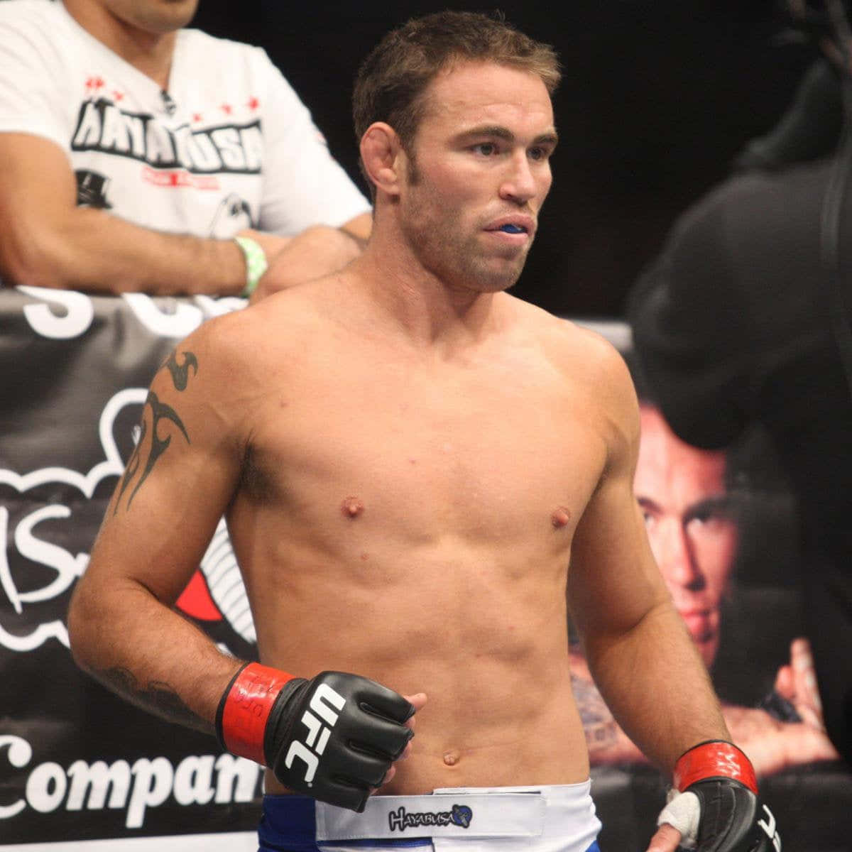 sport 桌布 壁紙 — 一位赤裸上身的男性混合武術家，帶有刺青和UFC手套，在搏擊擂台上強烈地站立。