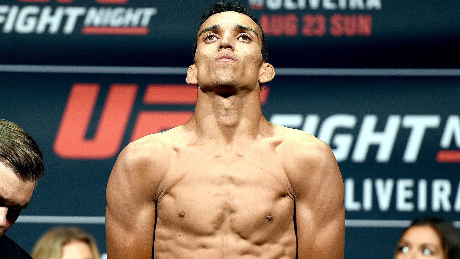 MMA 桌布 壁紙 — 一位赤裸上身的男拳手，在明亮燈光下自信地站在 UFC 稱重活動中。