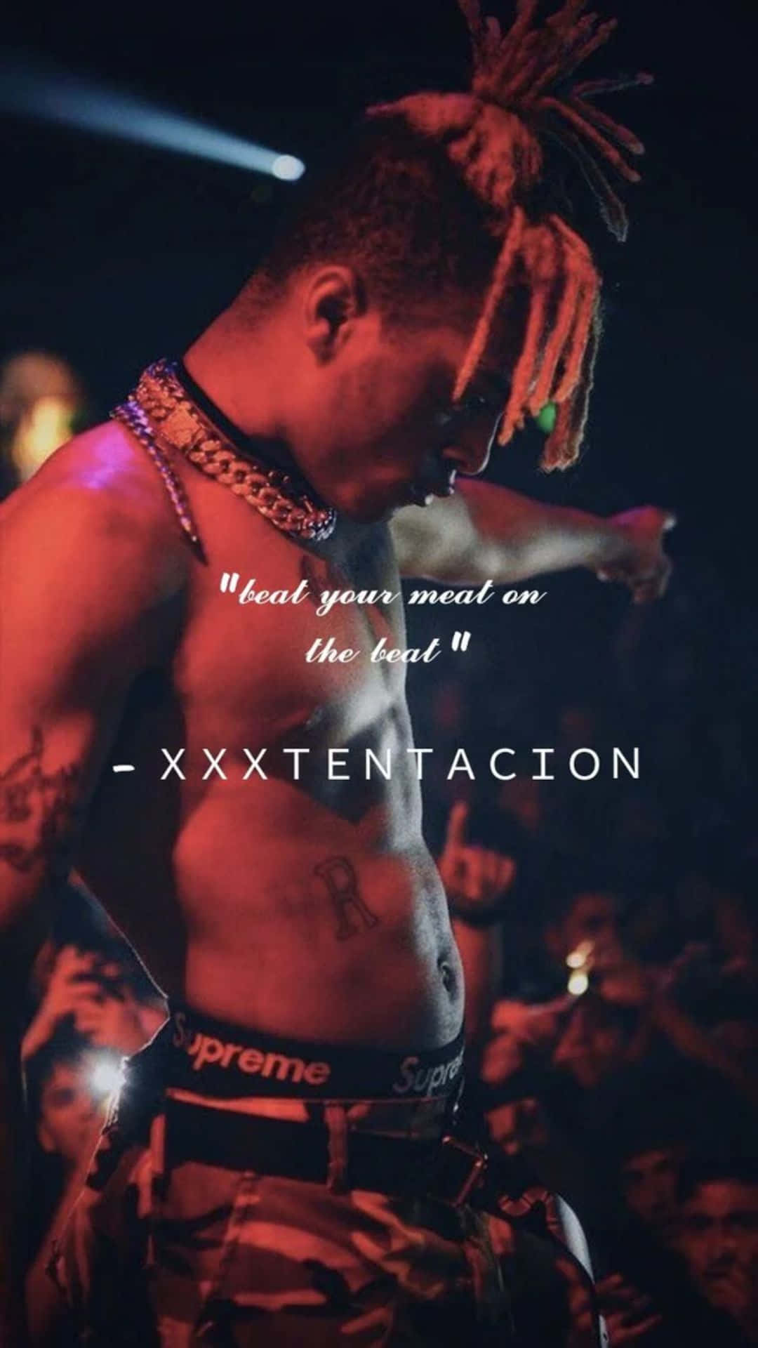 69 Rapper 桌布 壁紙 — 一位赤裸上身的辮子說唱歌手在紅色燈光下於舞台上表演，背景有觀眾。