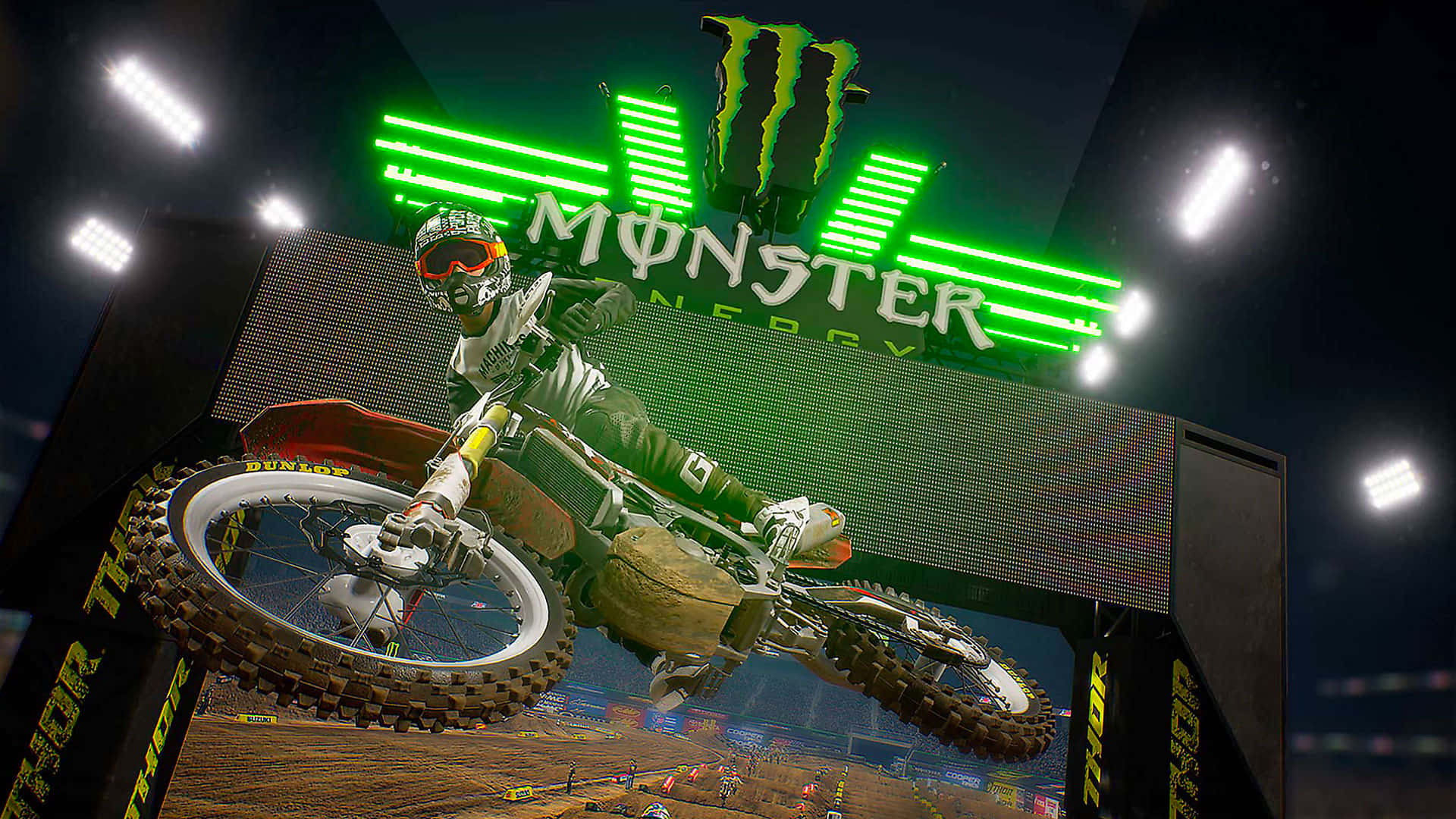 Monster Energy 桌布 壁紙 — 一位越野摩托車手在夜間體育館內，於發光的綠色Monster Energy標誌下飛翔。