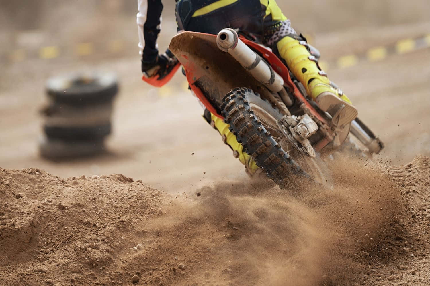 Dirtbike 桌布 壁紙 — 一位越野摩托車手在崎嶇的越野賽道上傾斜入急彎，揚起泥土。