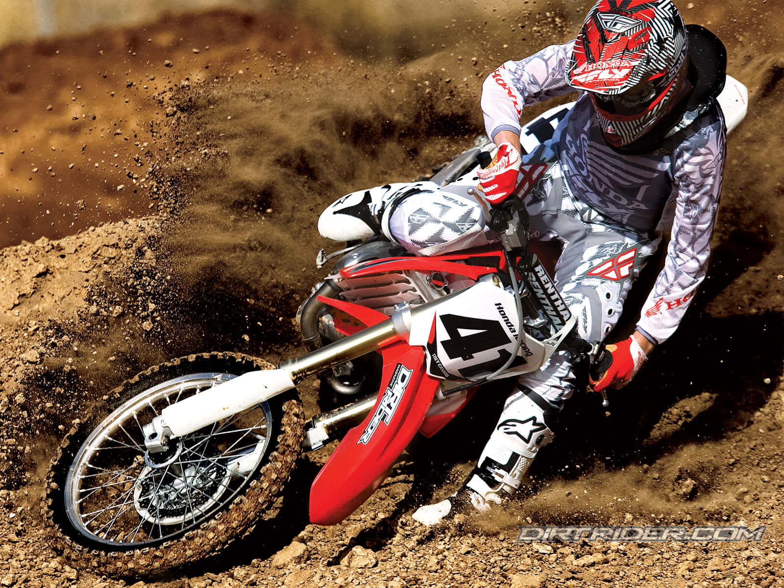 Honda Dirt Bike 桌布 壁紙 — 一位越野摩托車手在崎嶇賽道上騎著紅色越野車急轉彎，揚起棕色塵土。