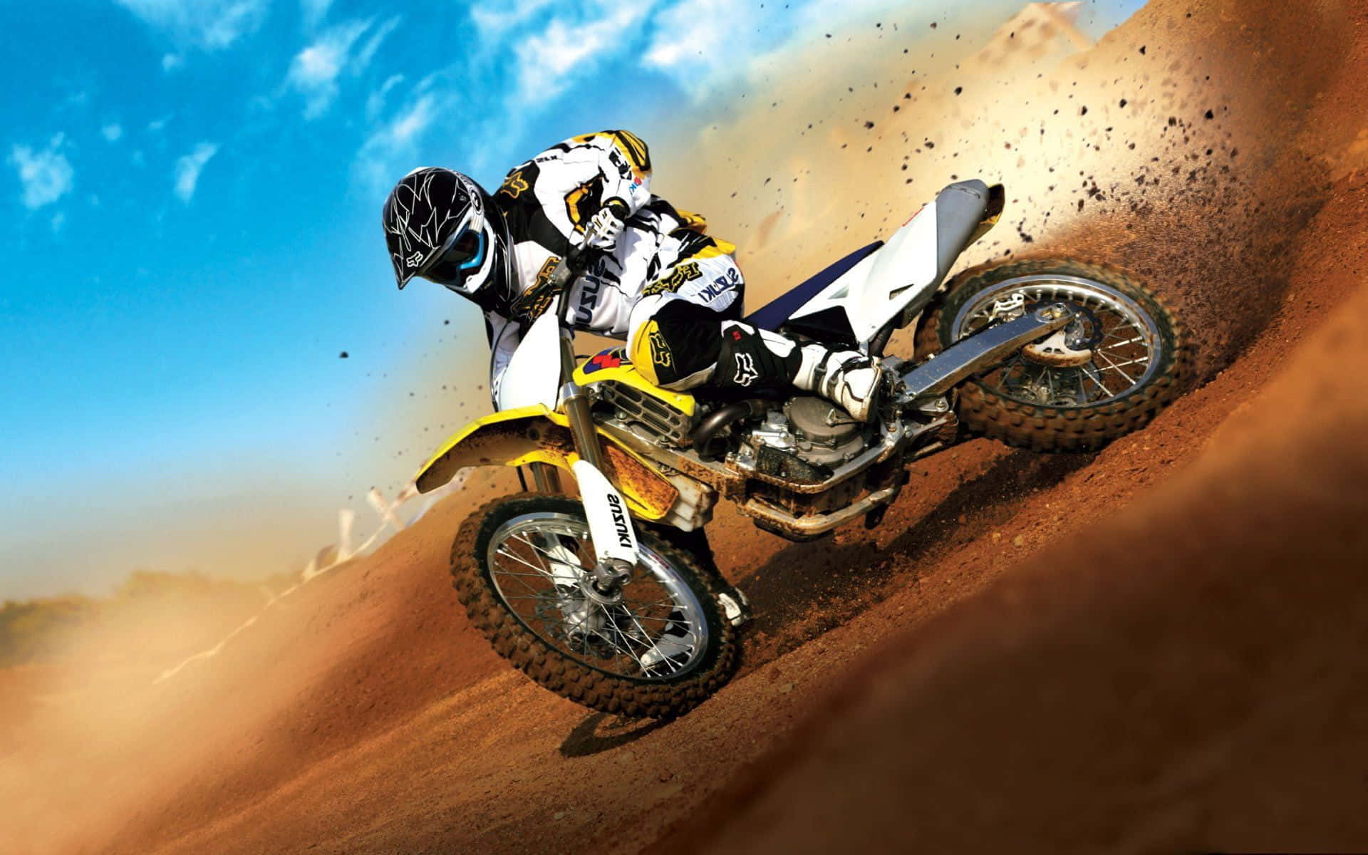 Motocross 桌布 壁紙 — 一位越野摩托車手在泥土賽道上傾斜入急彎，在明亮的藍天下揚起一片塵土。