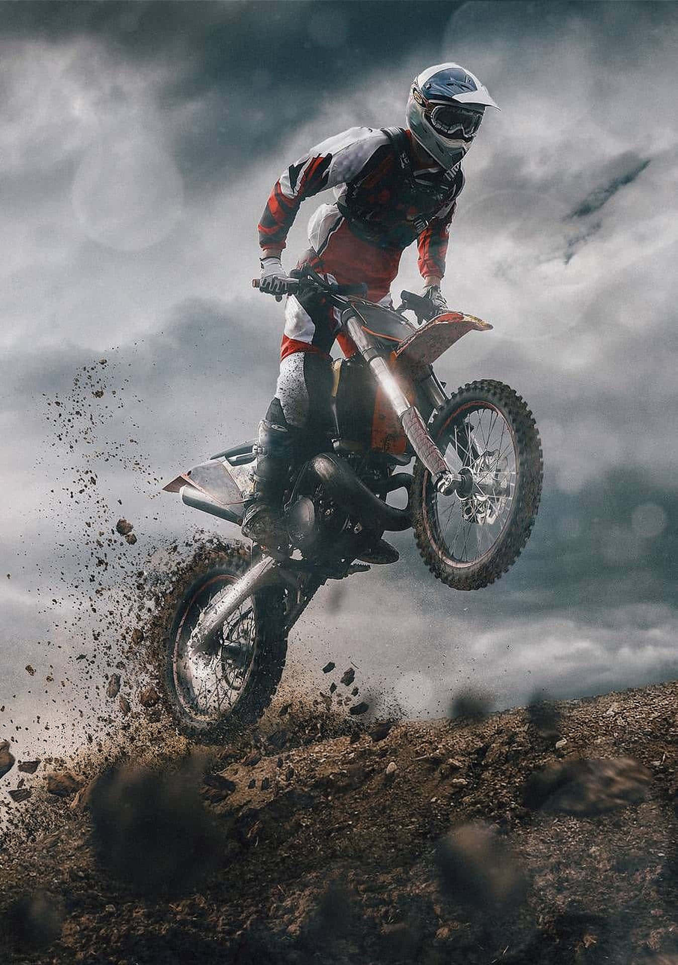 Honda Dirt Bike 桌布 壁紙 — 一位越野摩托車手在泥地摩托車上翱翔空中，下方泥漿四濺，背景是風暴般的灰色天空。
