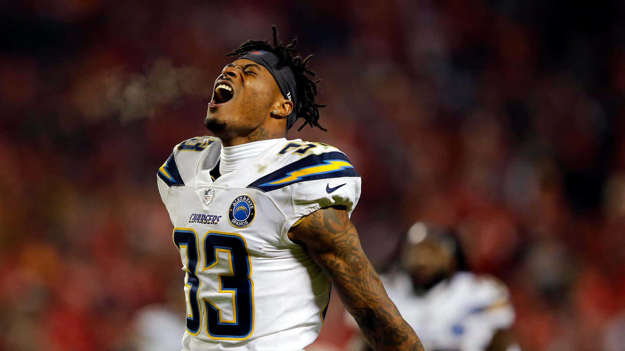 NFL 桌布 壁紙 — 一位身穿33號球衣的Chargers美式足球運動員在滿是紅色座位的體育館中勝利地吶喊。