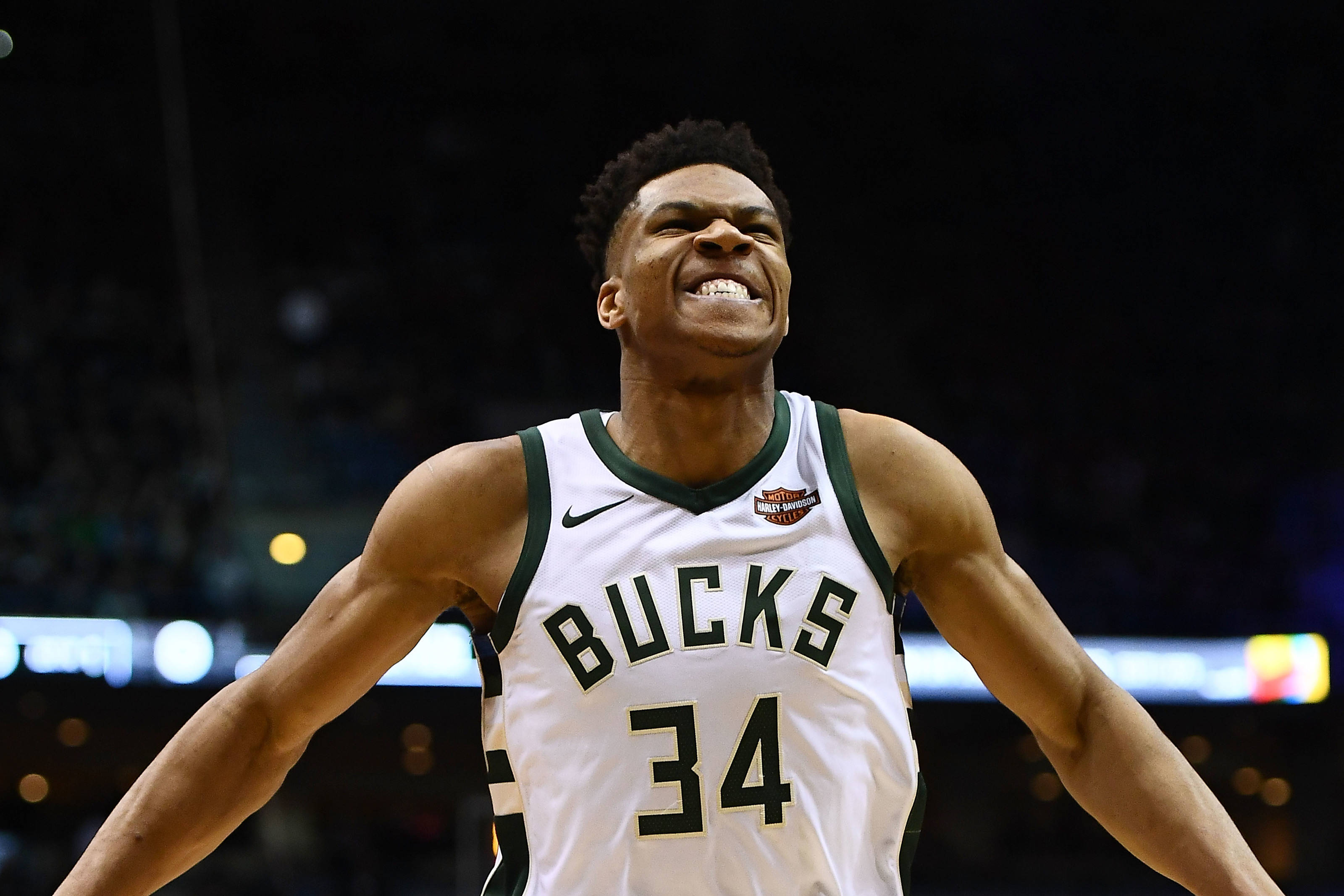 Giannis 桌布 壁紙 — 一位身穿34號球衣的密爾瓦基公鹿籃球運動員在場館燈光下張開雙臂慶祝。