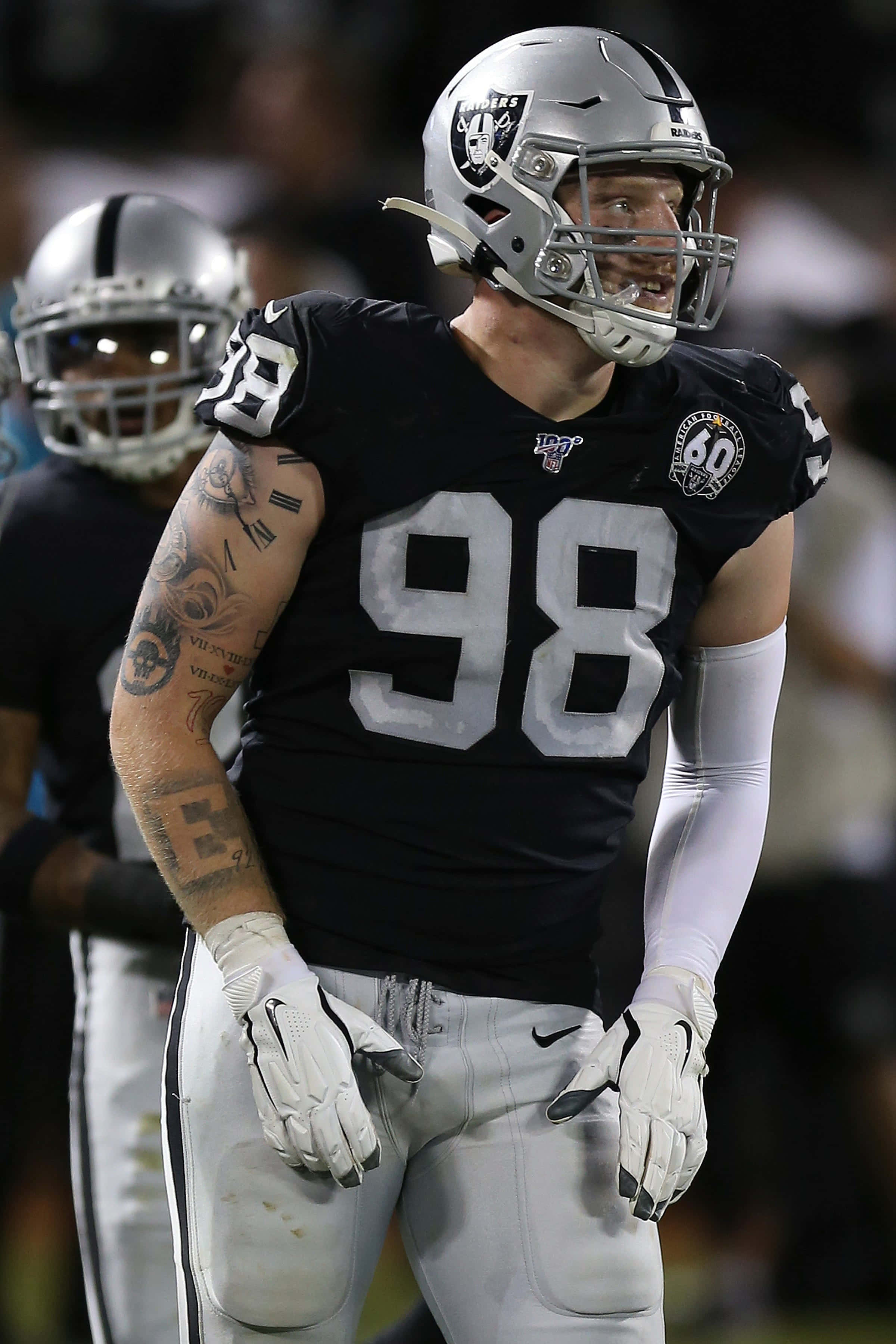 Las Vegas Raiders 桌布 壁紙 — 一位身穿98號球衣的拉斯維加斯突襲者美式足球員站在球場上，手臂上的刺青在體育場燈光下清晰可見。