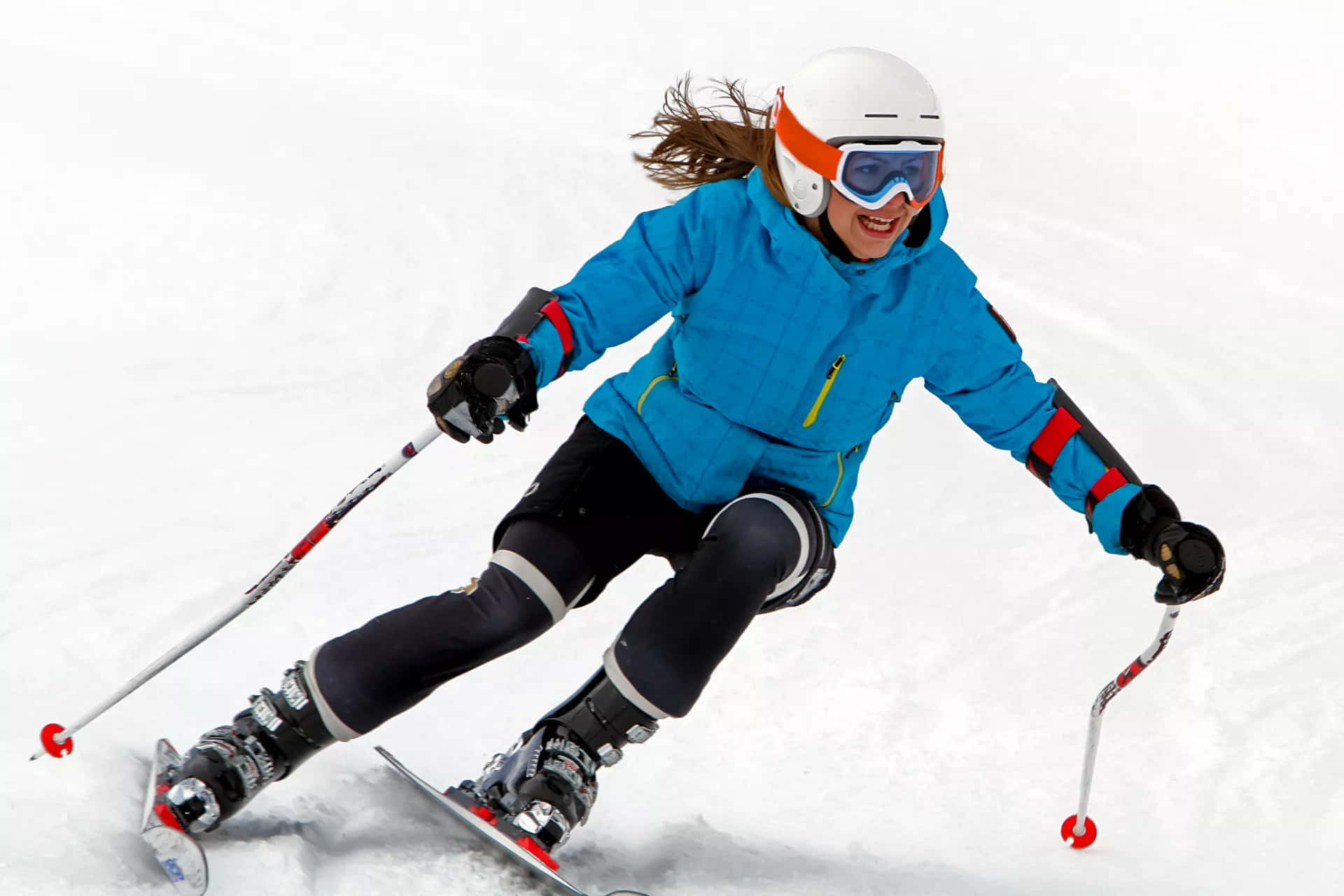 ski 桌布 壁紙 — 一位身穿亮藍色外套的快樂滑雪者，帶著動感活力和燦爛笑容在粉雪中滑行。