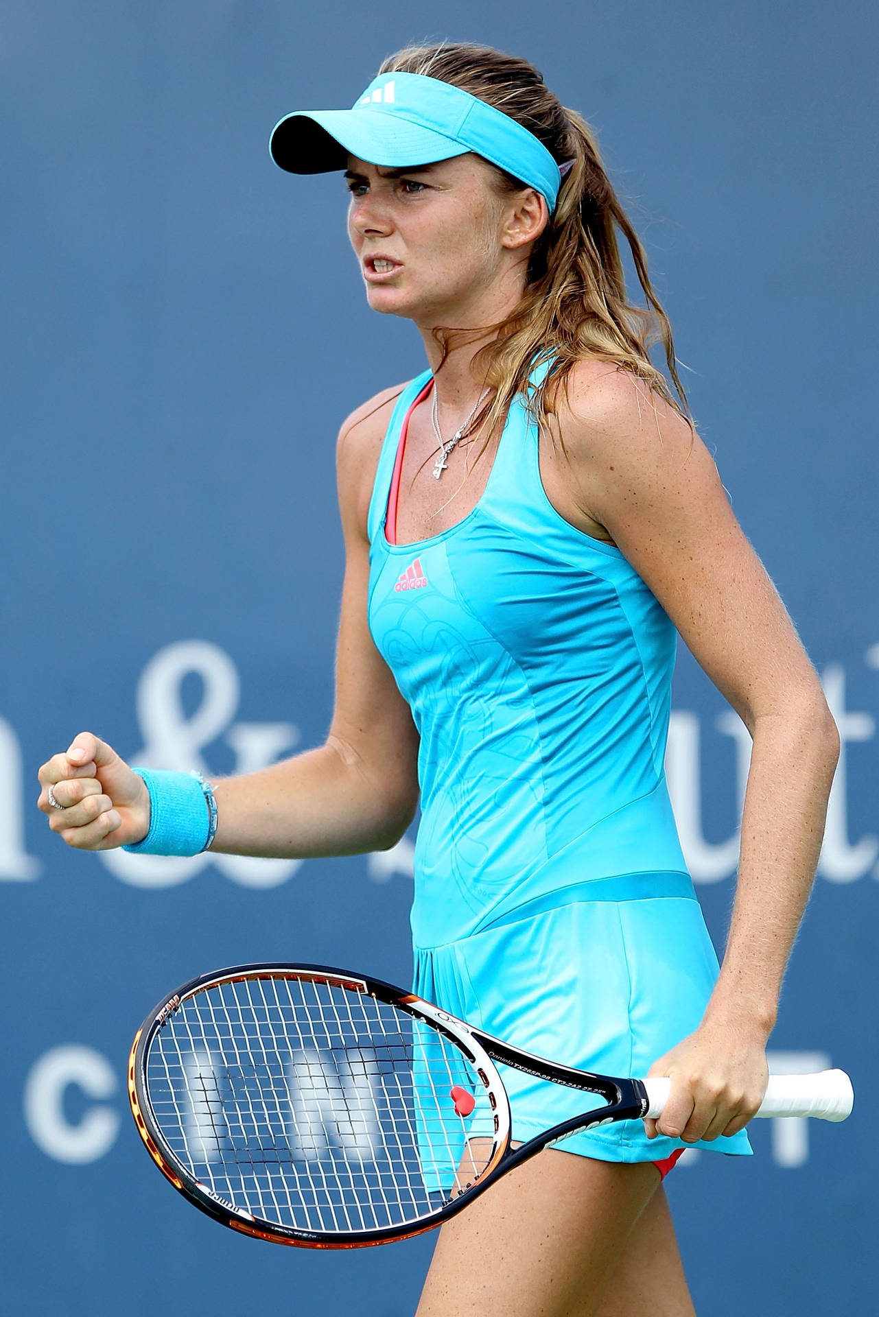 Tennis 桌布 壁紙 — 一位身穿亮藍色球衣的女網球運動員，在純藍色球場背景下握緊拳頭慶祝勝利，同時手持球拍。
