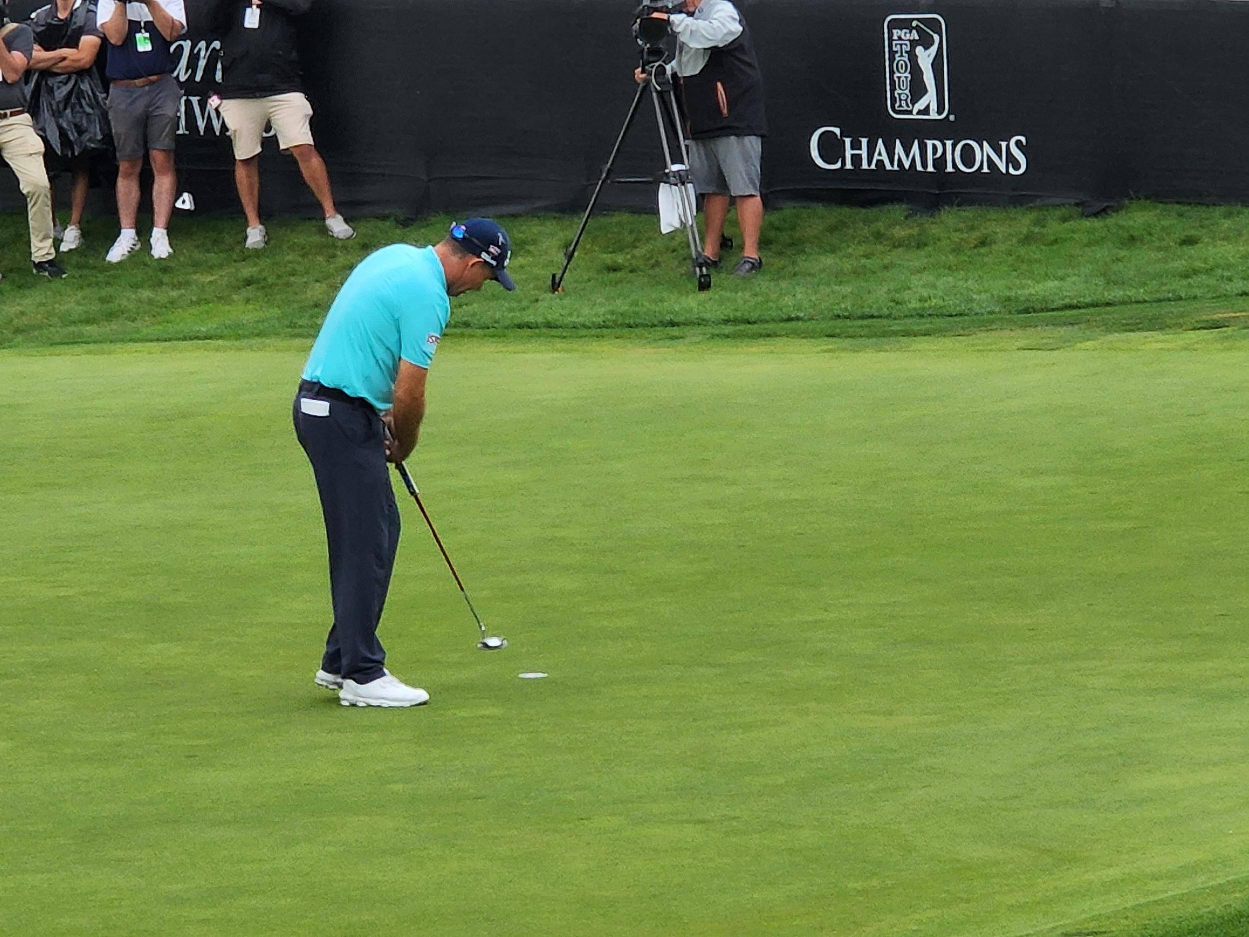 高爾夫 桌布 壁紙 — 一位身穿亮藍色襯衫的高爾夫球手在PGA TOUR Champions賽事中專注地在翠綠的球道上推桿。