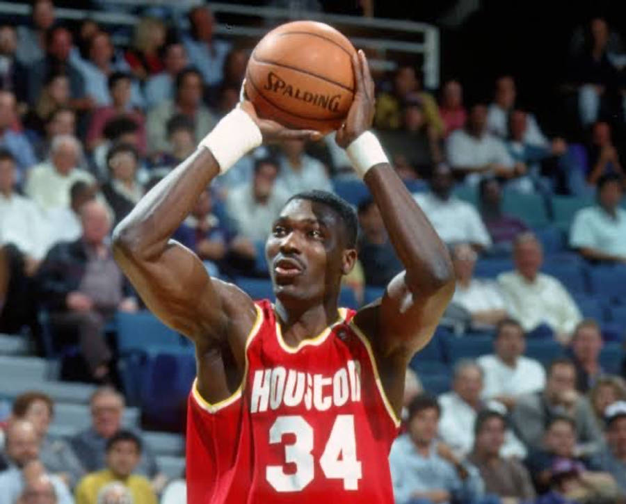 NBA 桌布 壁紙 — 一位身穿休士頓紅色34號球衣的籃球運動員在比賽中準備投擲Spalding籃球，背景是模糊的人群。