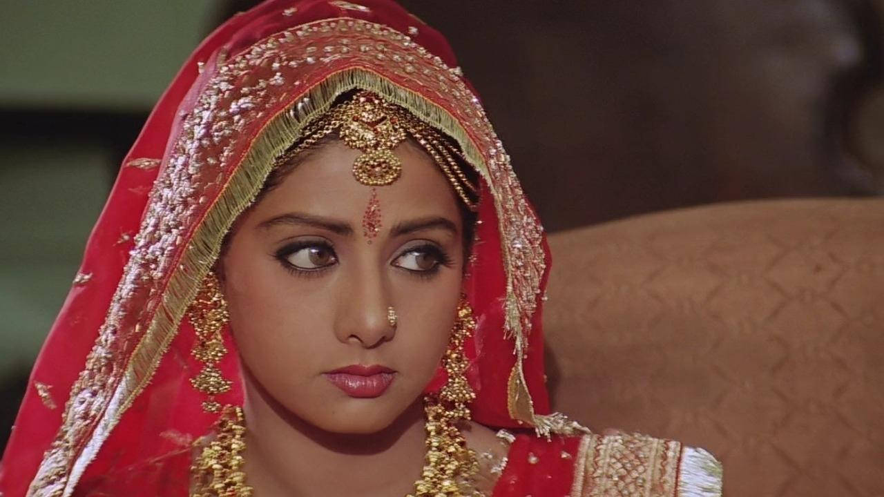 Sridevi 桌布 壁紙 — 一位身穿傳統印度新娘服飾、戴著紅色頭紗、金飾和眉心紅點的女性，若有所思地望向一旁。