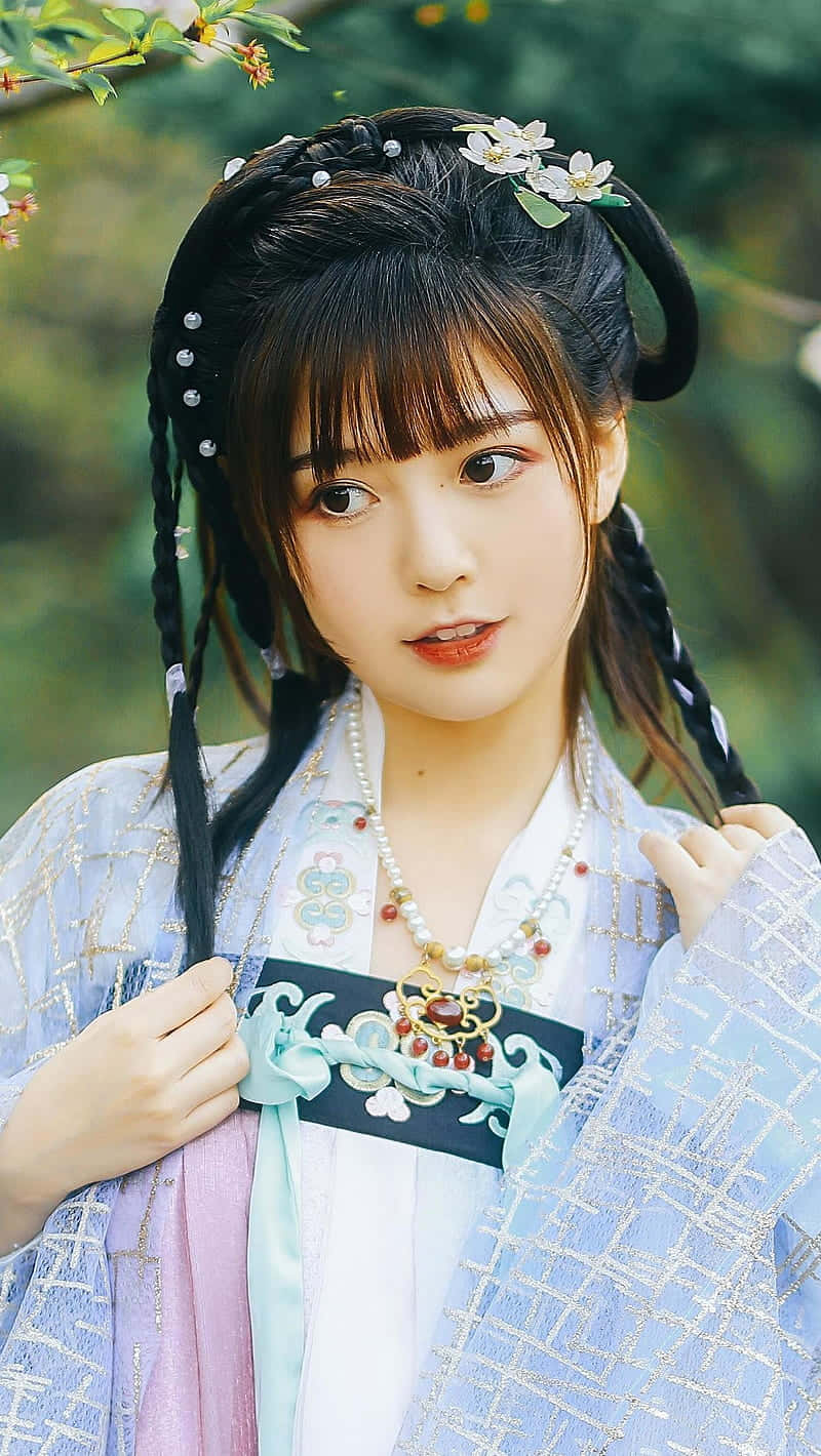 costume 桌布 壁紙 — 一位身穿傳統漢服、編織辮子點綴花朵的年輕女性，在模糊的綠色花園背景下溫柔微笑。
