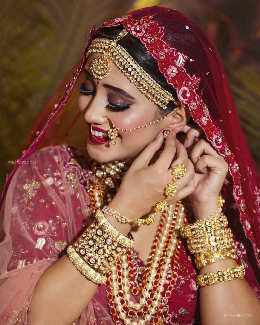 Bridal 桌布 壁紙 — 一位身穿傳統紅色和金色婚紗的新娘微笑著調整她的珠寶。