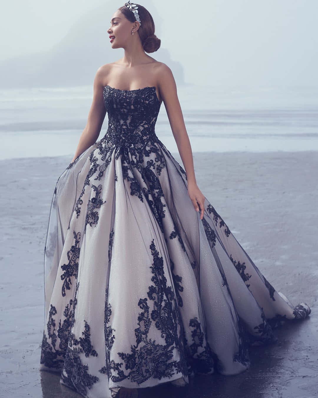 Black And White Wedding 桌布 壁紙 — 一位身穿優雅黑白蕾絲長裙的女性，身後有海浪拍打，優雅地站在霧氣瀰漫的海灘上。