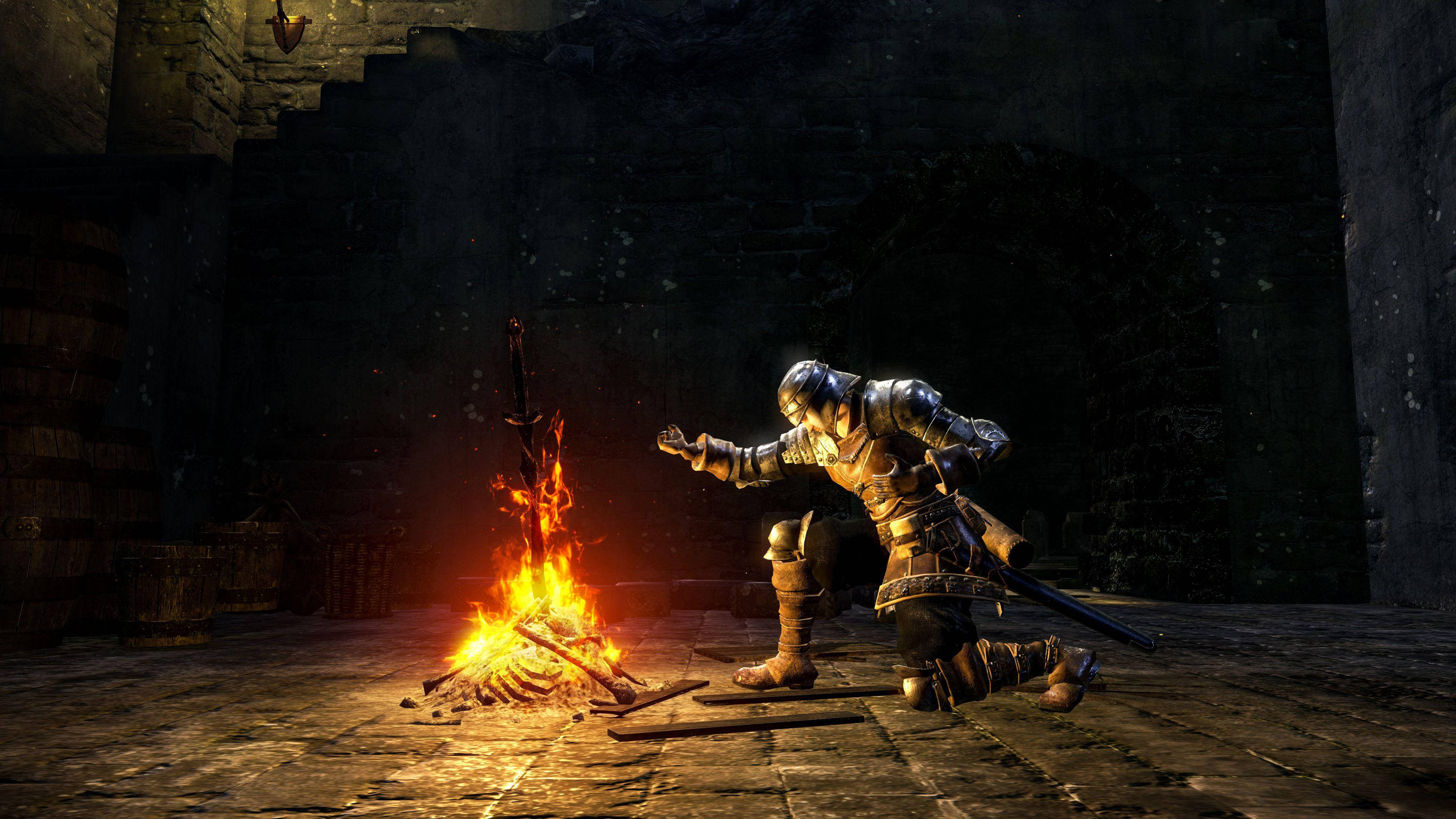 dark souls 4K 桌布 壁紙 — 一位身穿全副盔甲的騎士在昏暗的石頭地牢中跪在熊熊燃燒的營火前，溫暖的光芒映照在古老的石牆和木桶上。