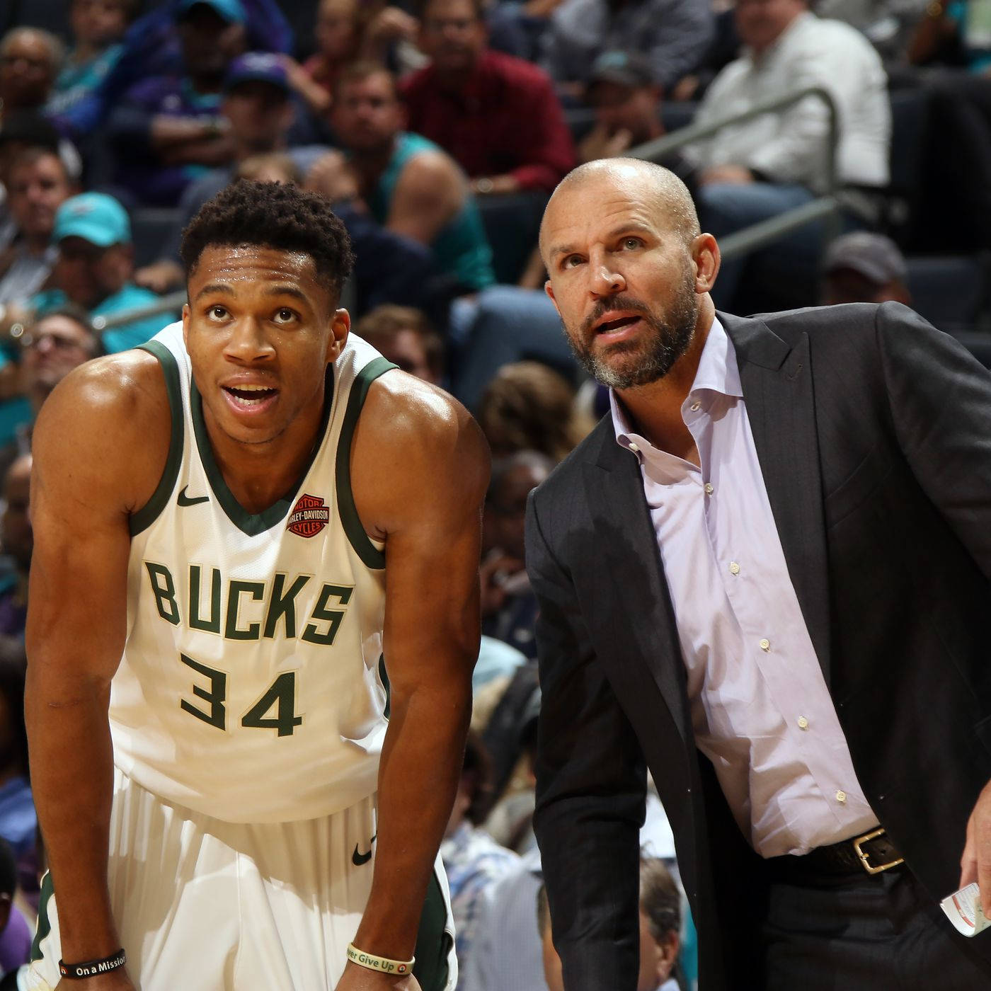 NBA 桌布 壁紙 — 一位身穿公鹿隊球衣的專注籃球運動員在比賽中靠前，站在教練旁邊，背景有觀眾。