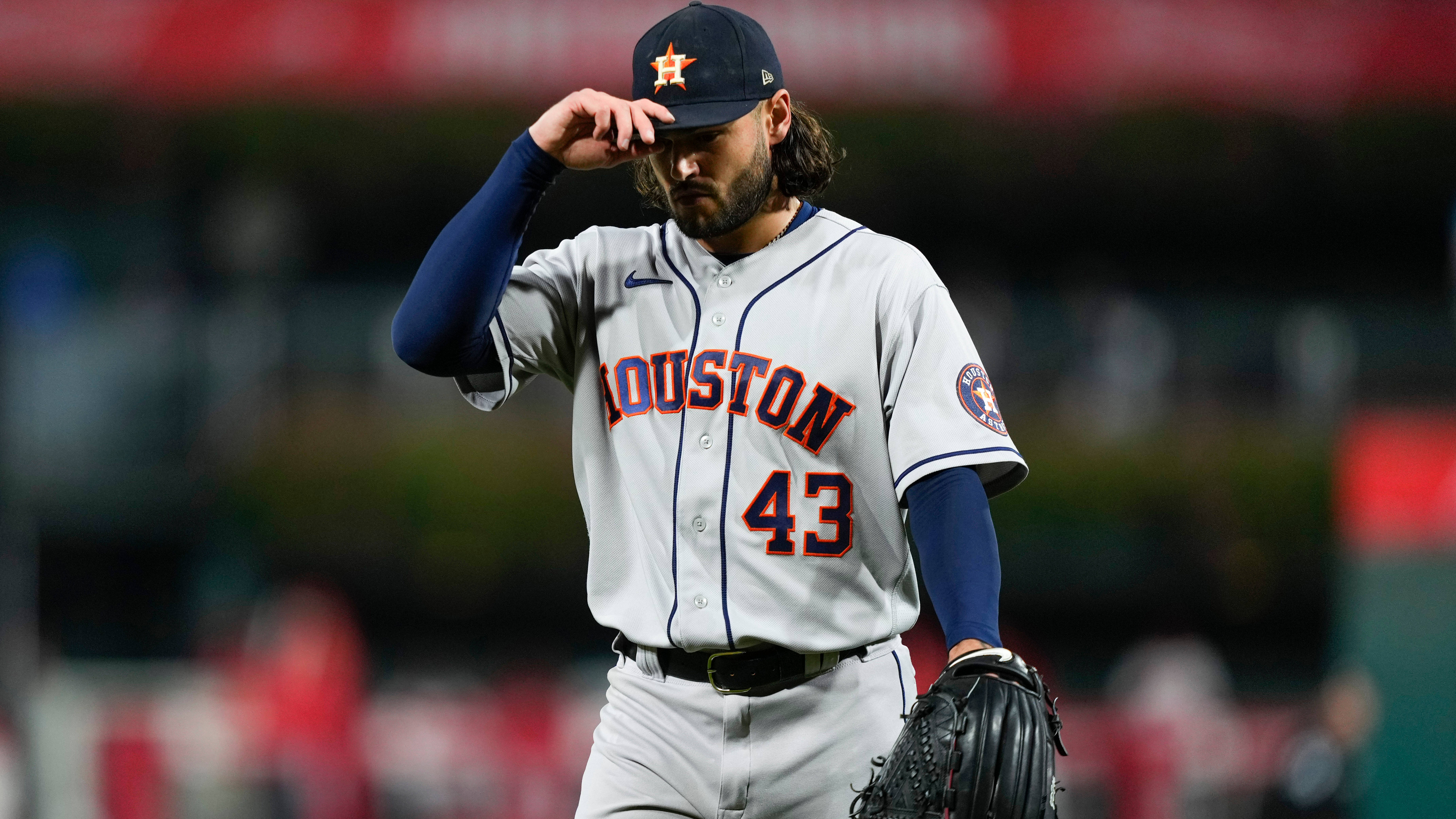 Houston Astros 桌布 壁紙 — 一位身穿制服的休士頓太空人棒球選手在球場燈光下，專注地調整他的帽子。