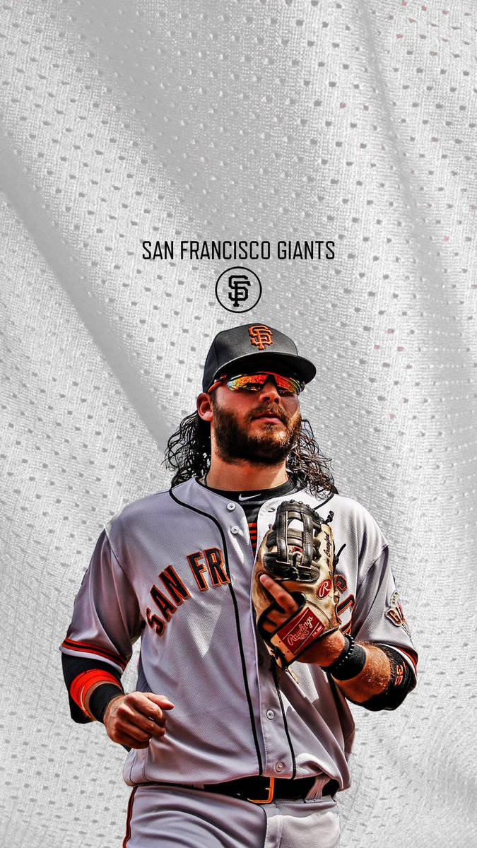 San Francisco Giants 桌布 壁紙 — 一位身穿制服的舊金山巨人隊棒球運動員自信地站在帶有球隊品牌的紋理背景前。