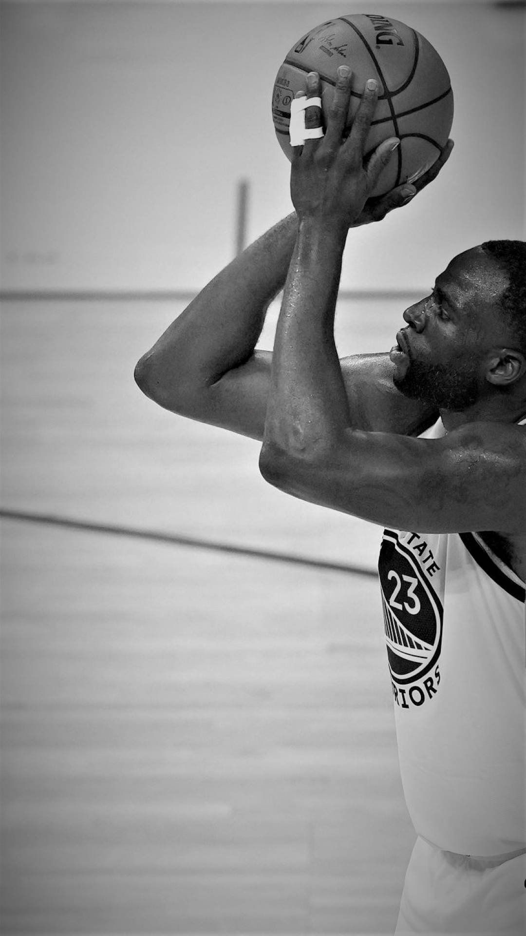 Draymond Green 桌布 壁紙 — 一位身穿勇士隊球衣的籃球運動員在單色調的體育館中準備投罰球。