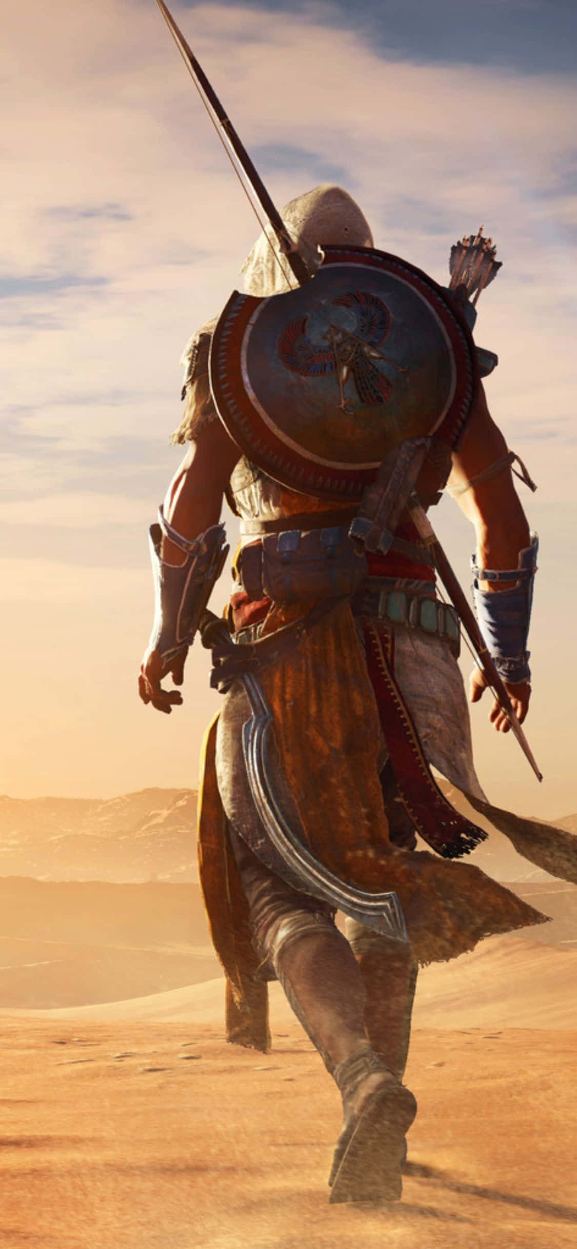 iPhone X Assassin's Creed Origins 桌布 壁紙 — 一位身穿古代盔甲的戰士，手持盾牌和劍，在陽光明媚的沙漠中大步前行。