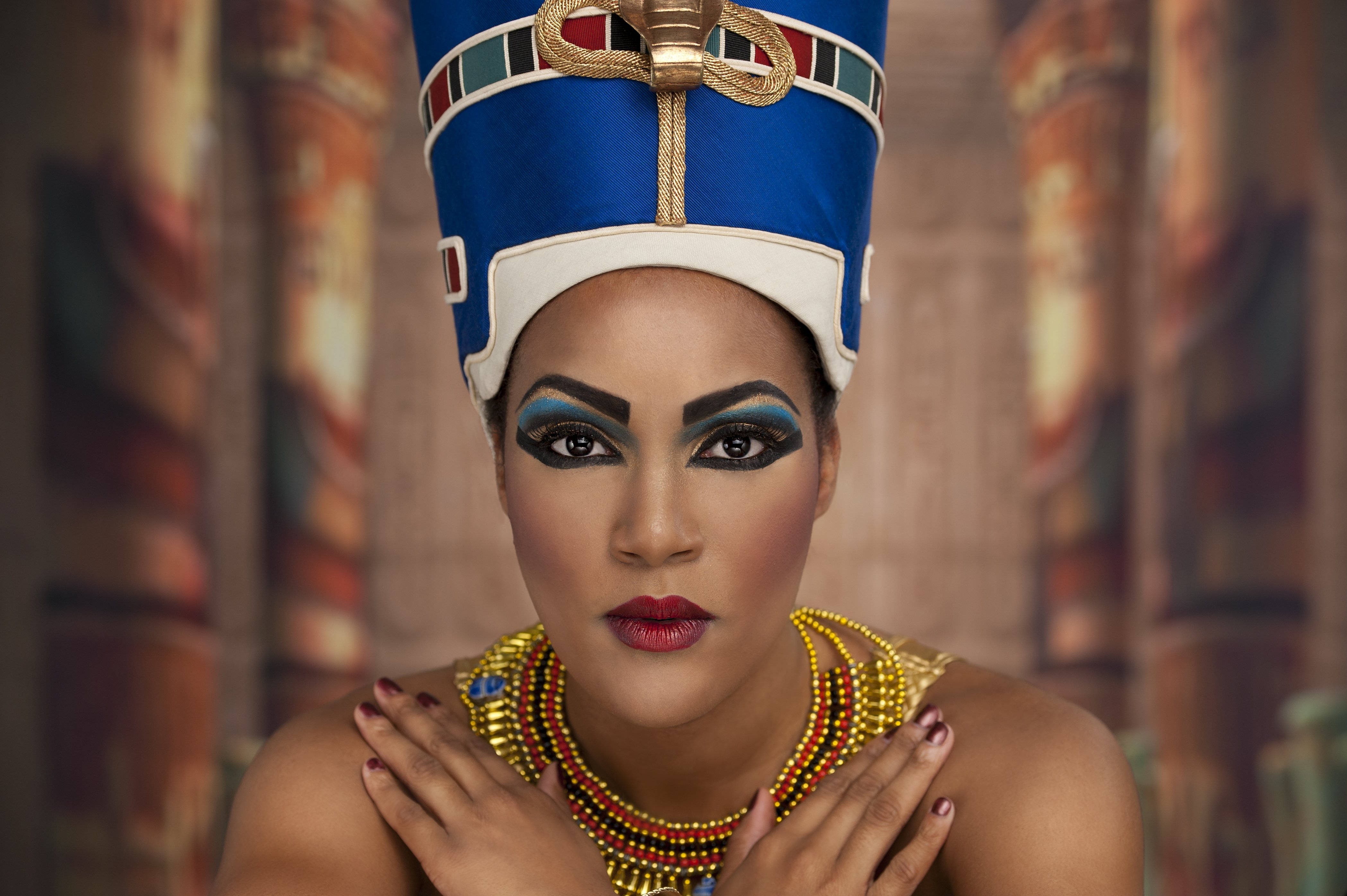 Cleopatra 桌布 壁紙 — 一位身穿古埃及服飾、化著大膽妝容、佩戴金色珠寶的女子直視觀眾。