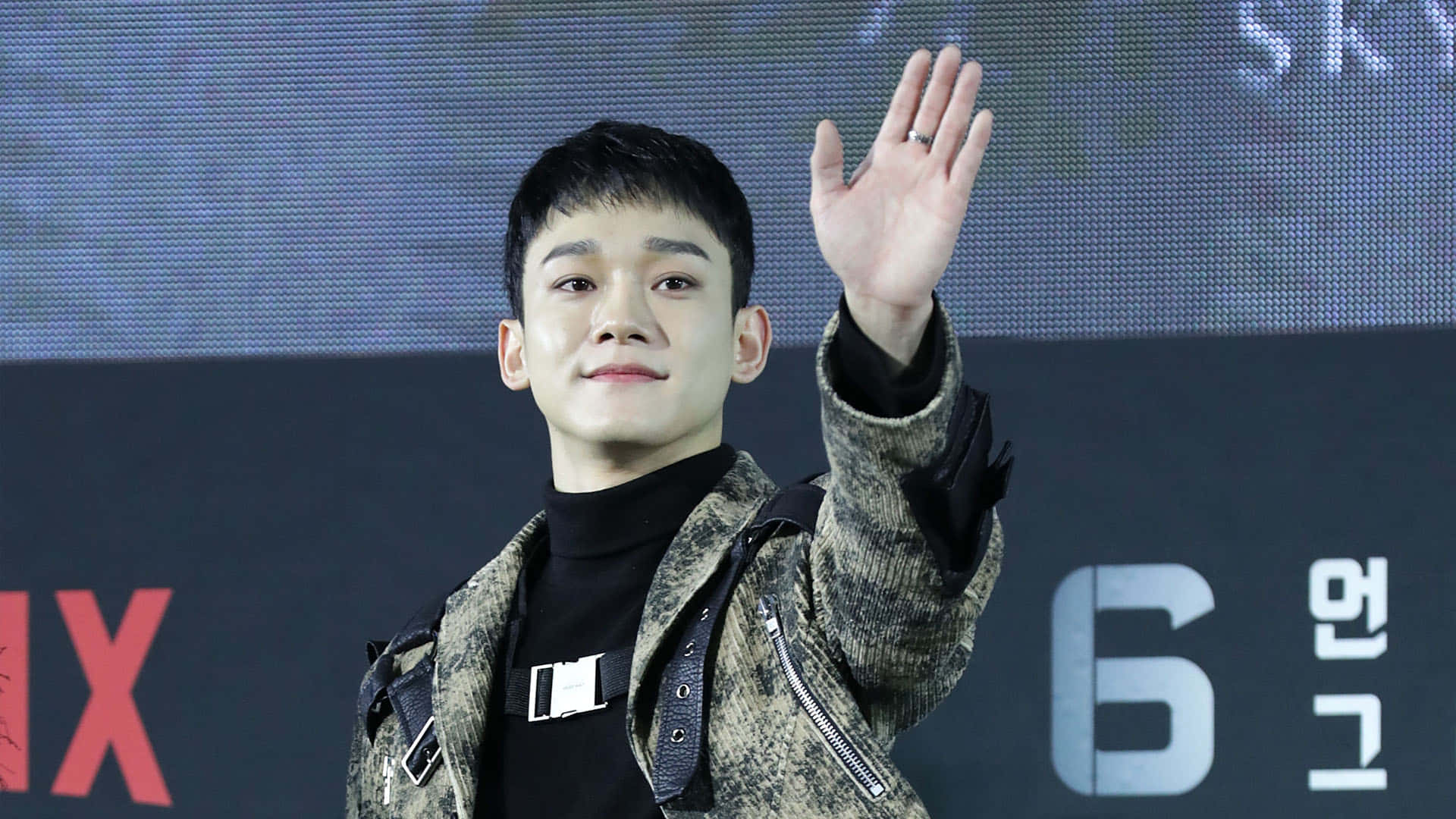 EXO 桌布 壁紙 — 一位身穿圖案外套的年輕人在Netflix活動背景前開心地揮手。