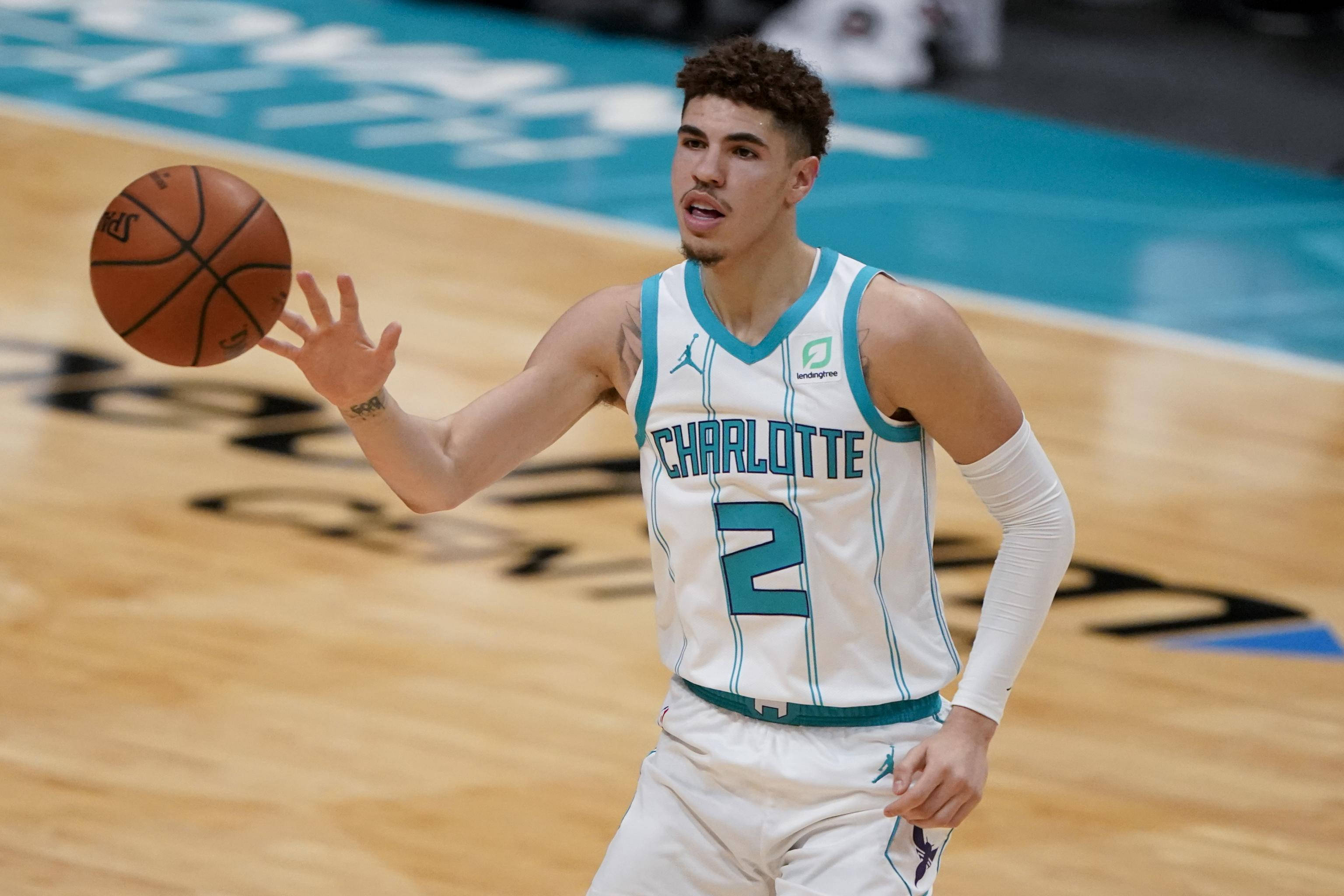 ball 桌布 壁紙 — 一位身穿夏洛特球衣的籃球運動員在硬木球場上運球比賽。