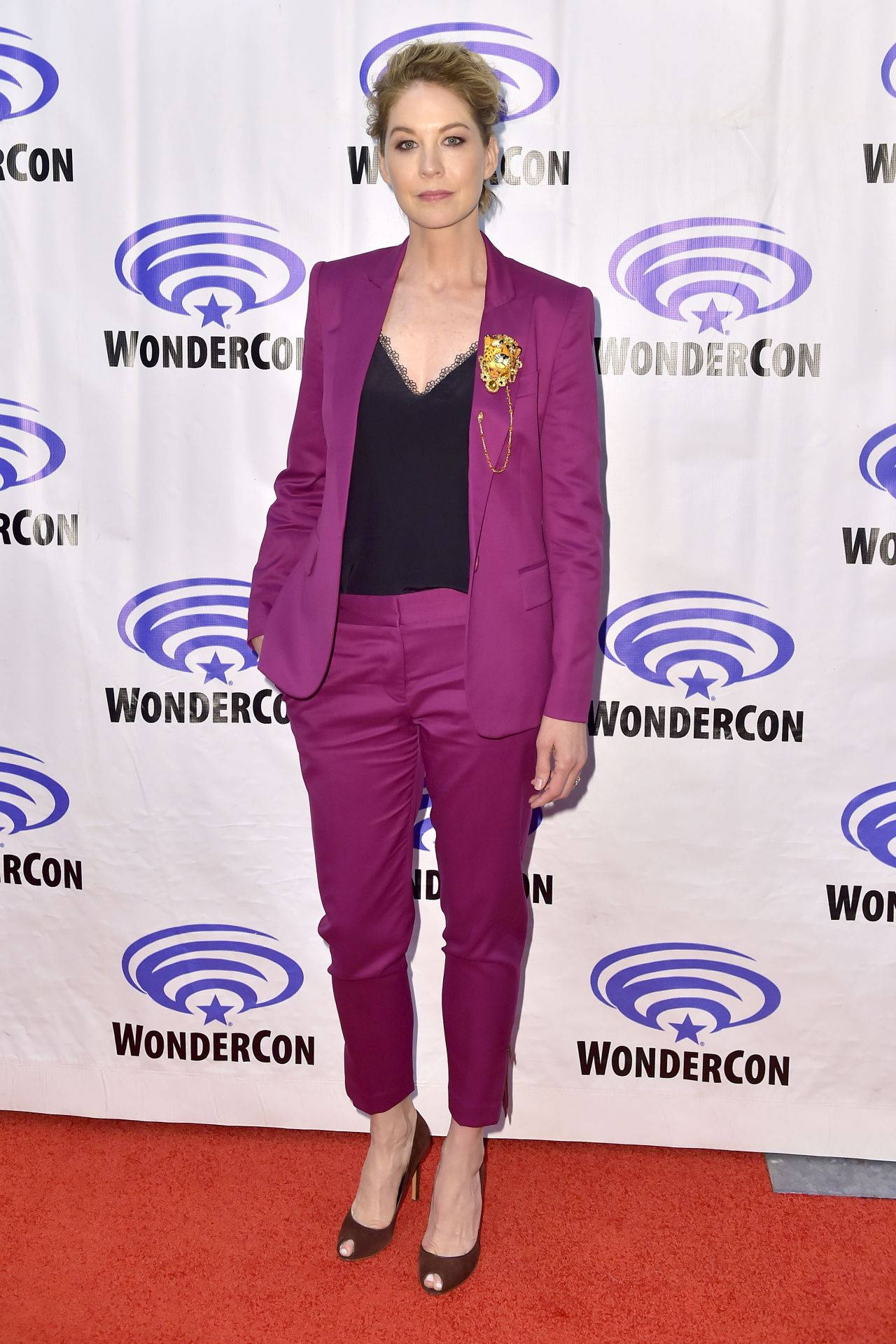 陰屍路 桌布 壁紙 — 一位身穿大膽洋紅色西裝的女性在 WonderCon 品牌背景前的紅地毯上擺姿勢。