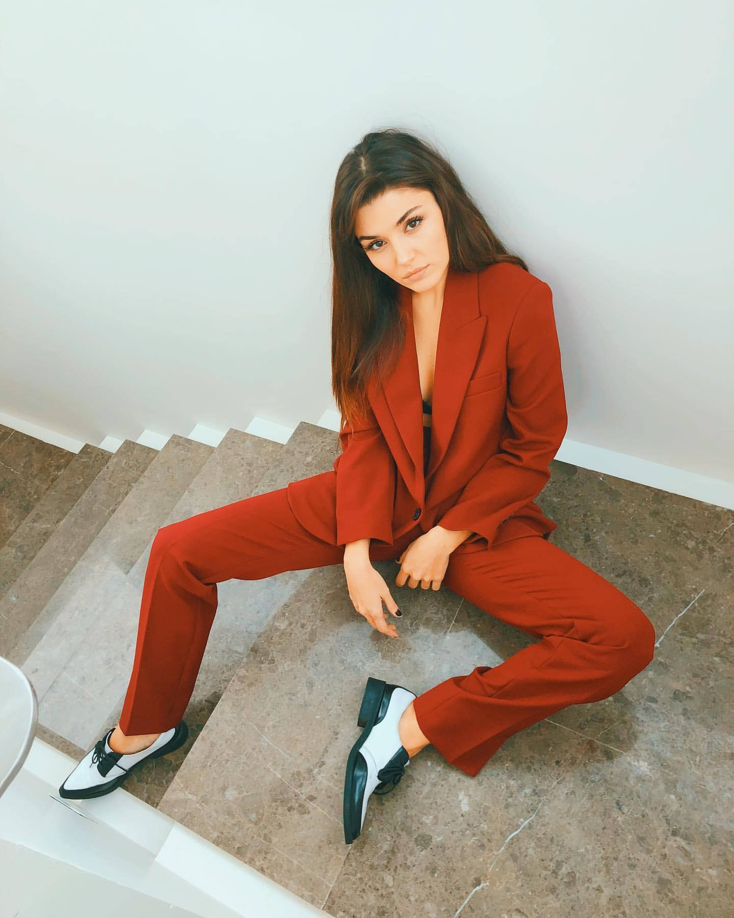 女演員 桌布 壁紙 — 一位身穿大膽紅色西裝的女性自信地坐在白色牆壁前的大理石樓梯上。