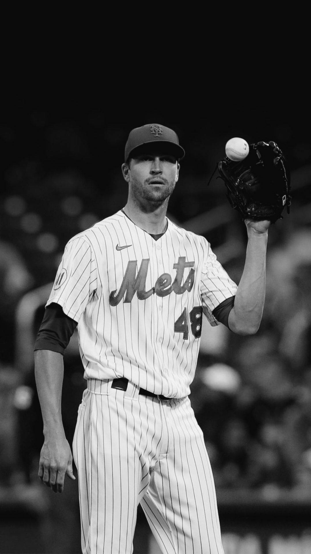 Degrom 桌布 壁紙 — 一位身穿大都會隊球衣的棒球投手在球場燈光下，以黑白畫面握著手套中的球。