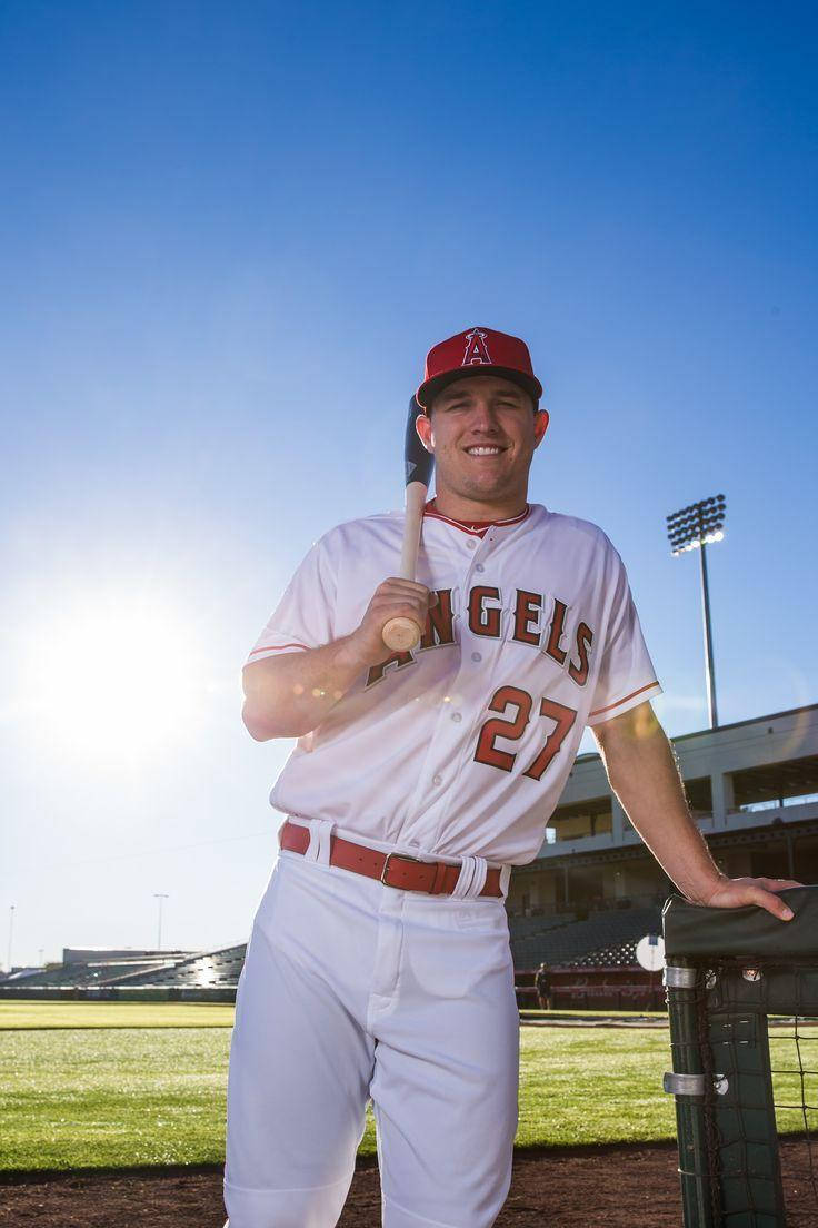 身穿天使隊制服的棒球選手在陽光明媚的球場上微笑拿著球棒。 — Michael B Jordan 壁紙