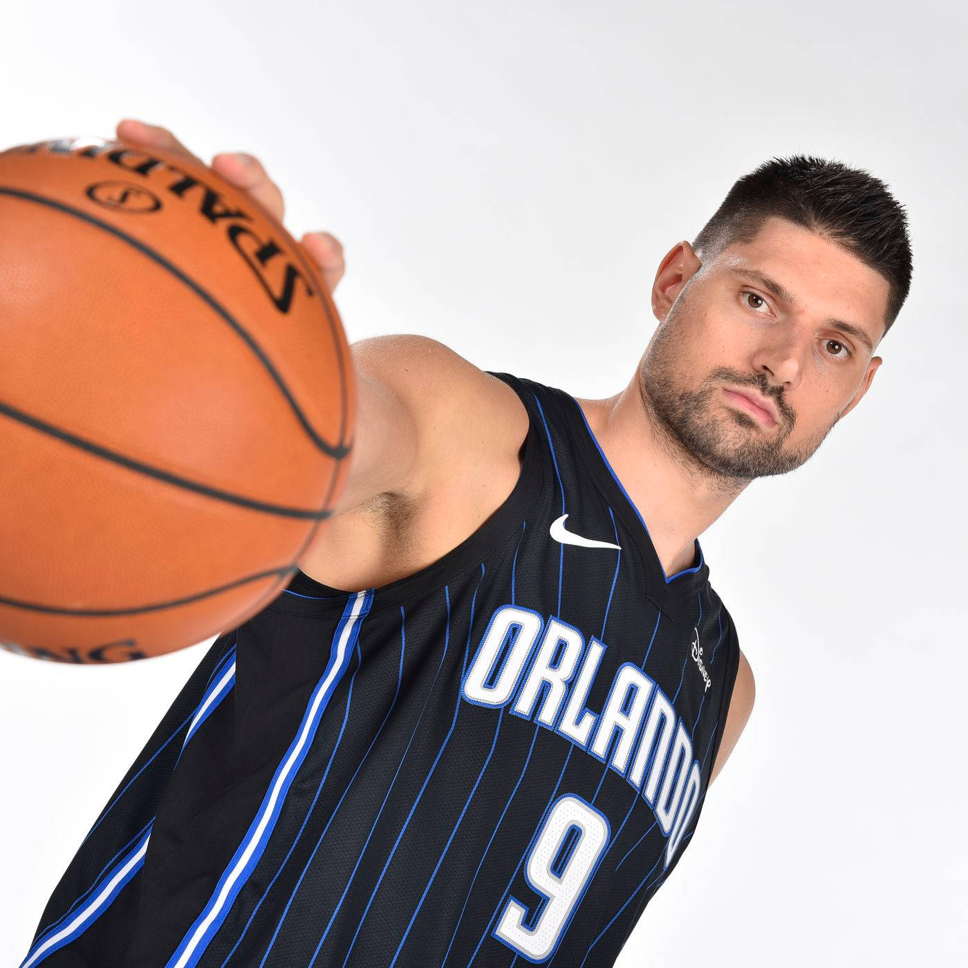 NBA 桌布 壁紙 — 一位身穿奧蘭多球衣的籃球運動員，在純白背景下專注地拿著一個Spalding籃球。