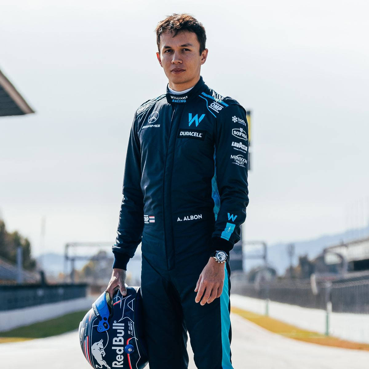 Athlete 桌布 壁紙 — 一位身穿威廉姆斯車隊賽車服的F1車手自信地站在賽道上，手持他的紅牛頭盔。