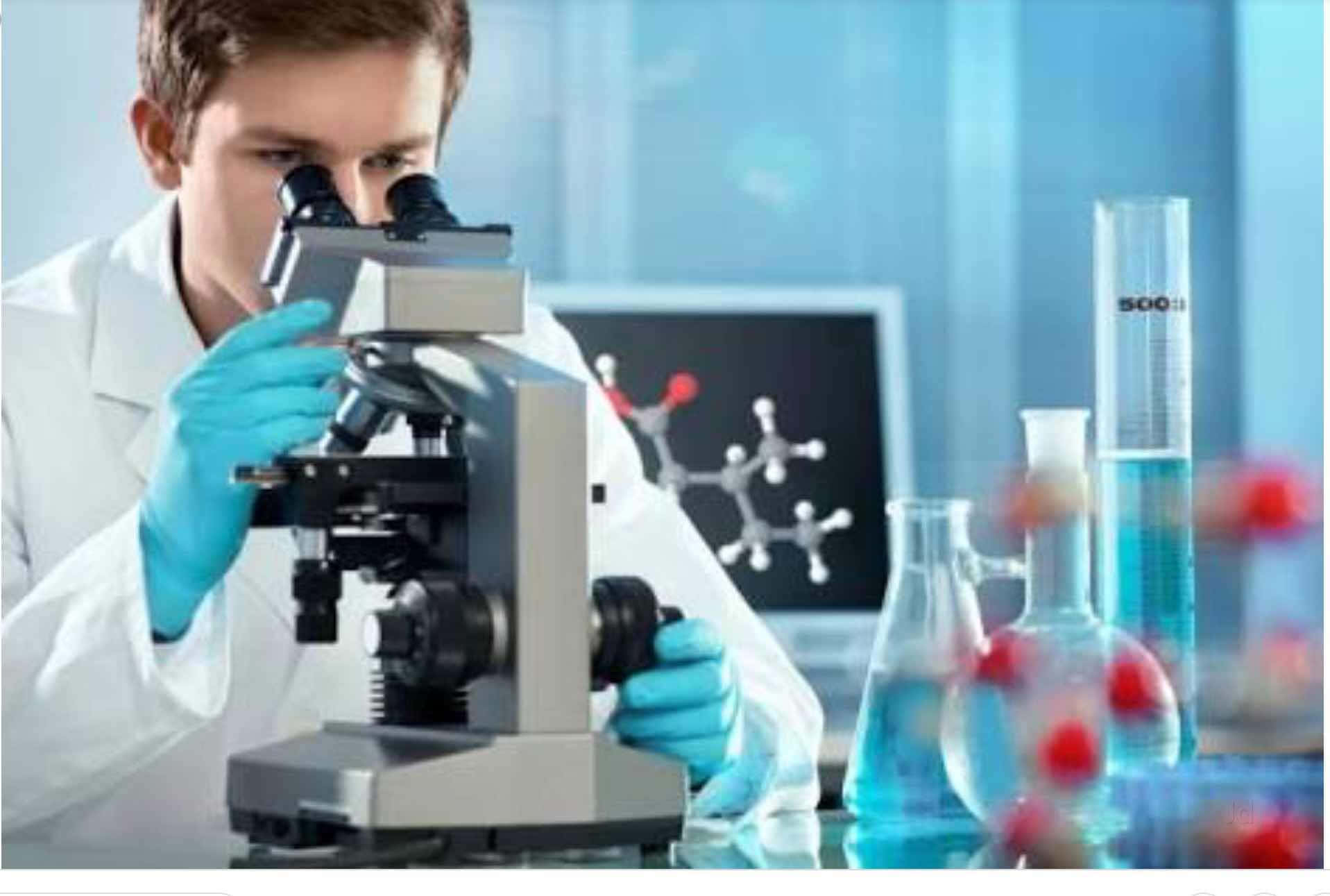 Lab 桌布 壁紙 — 一位身穿實驗袍和藍色手套的年輕科學家，在燒杯和分子模型環繞下，專注地透過顯微鏡觀察。