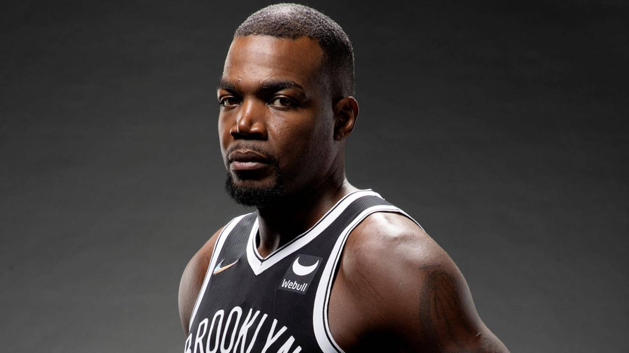 paul millsap 桌布 壁紙 — 一位身穿布魯克林籃網隊球衣的專注籃球運動員，在黑暗的攝影棚背景下凝視著。
