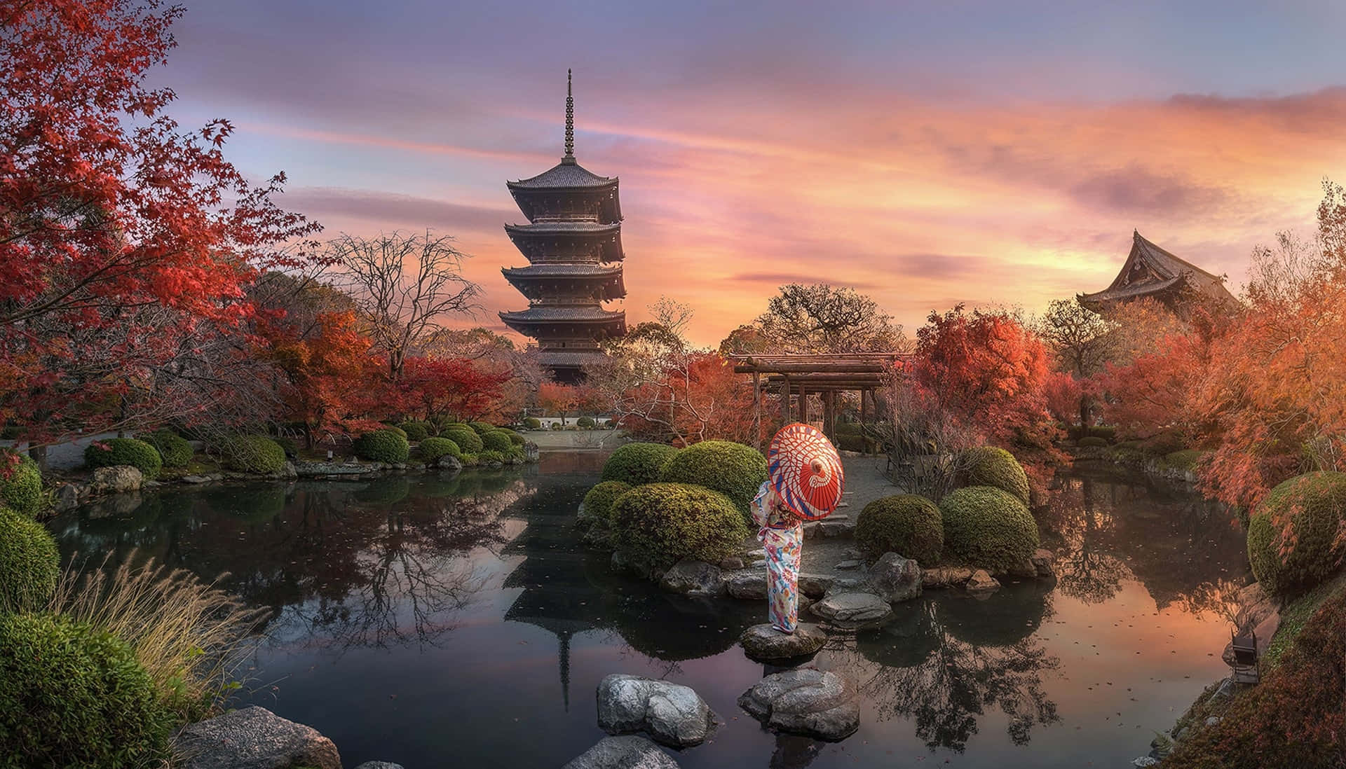 Samurai Garden 桌布 壁紙 — 一位身穿彩色和服的女士，手持圖案雨傘，站在日落時分寧靜的日本庭園岩石上，寶塔倒映在池塘中。