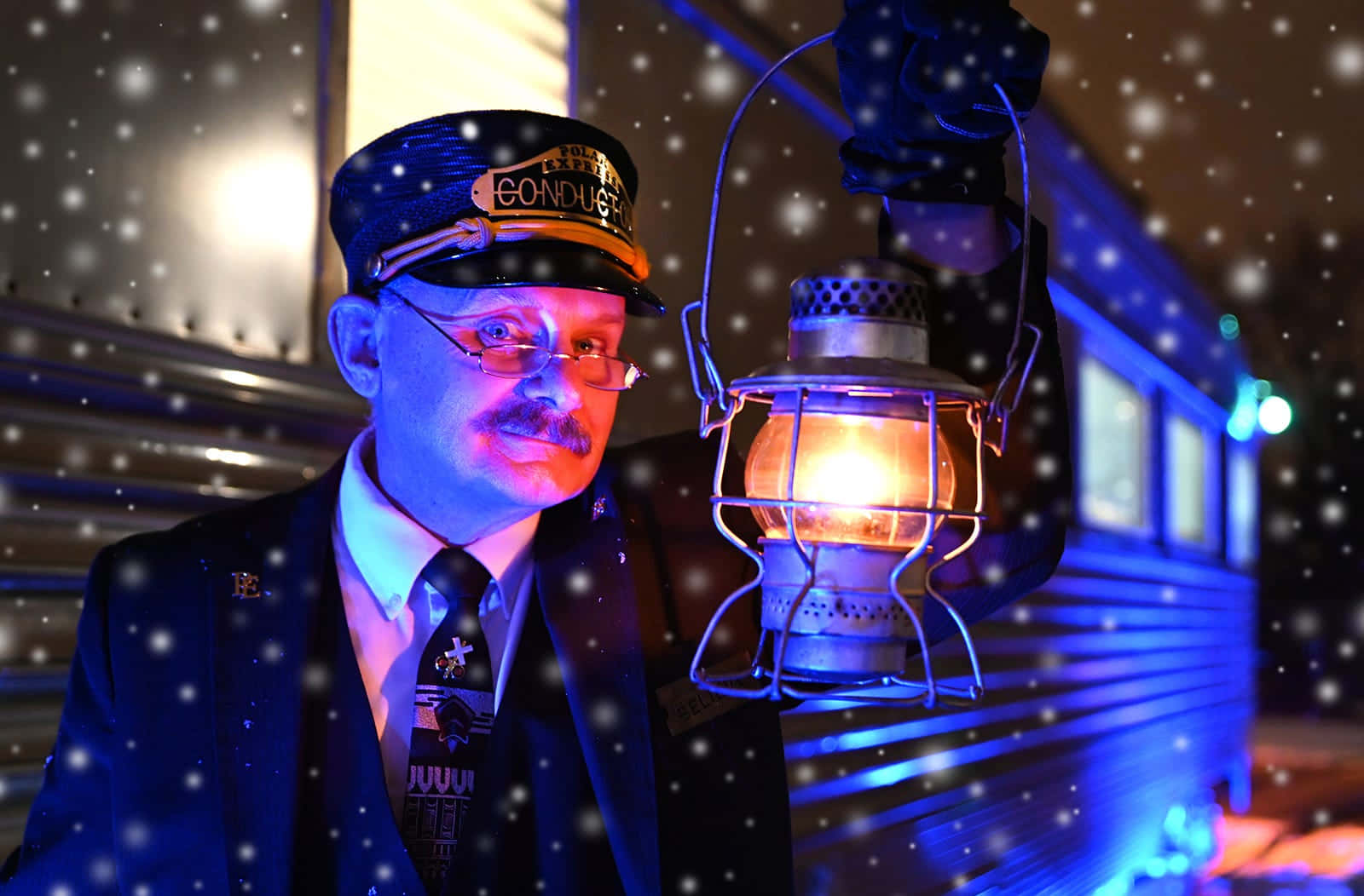 Polar Express 桌布 壁紙 — 一位身穿復古制服的列車長在雪夜背景下，身後有一列火車，手持發光燈籠。