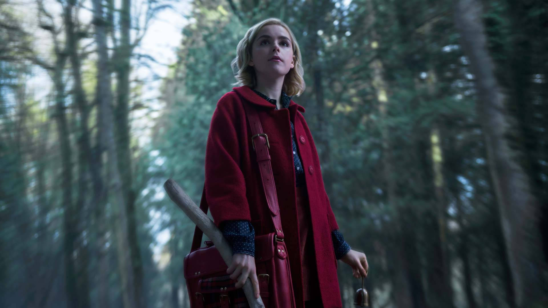 maeve wiley 桌布 壁紙 — 一位身穿搶眼紅色外套的女性，站在迷霧森林中，手持棒球棍和一個紅色手提包。