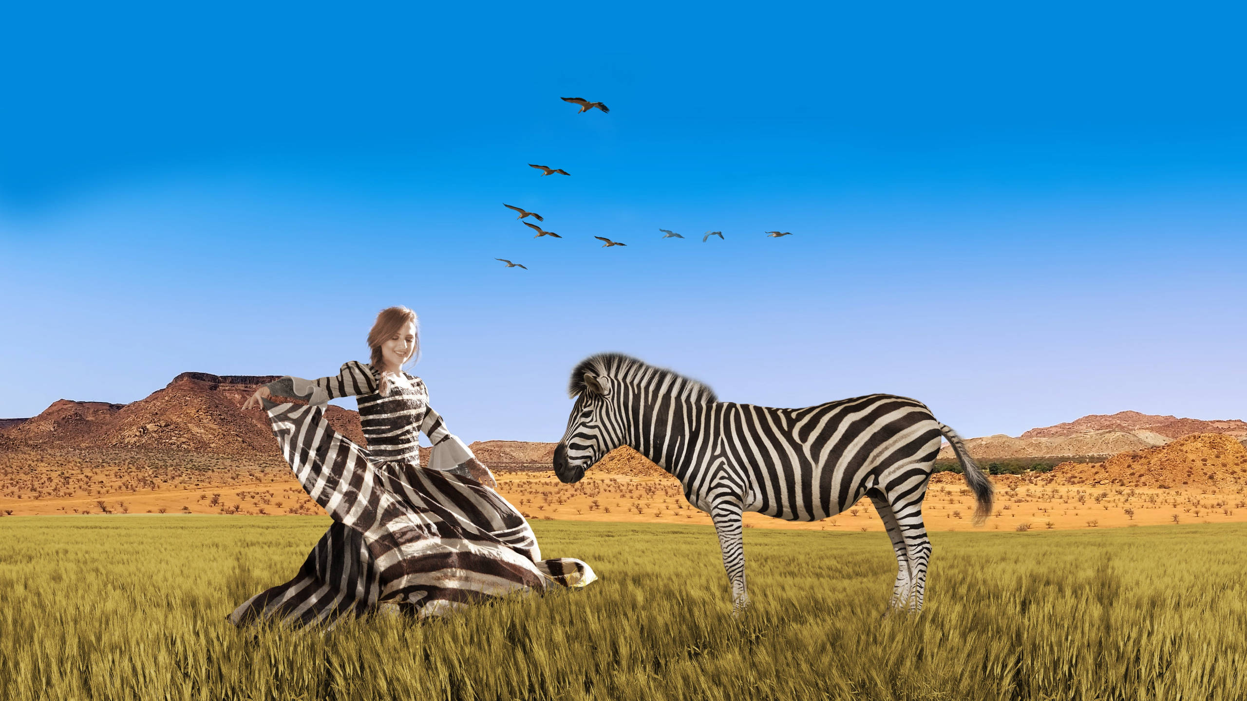 Zebra 桌布 壁紙 — 一位身穿斑馬條紋連衣裙的女性坐在斑馬旁邊，身處長滿草的稀樹草原，頭頂是晴朗的藍天，鳥兒在飛翔。